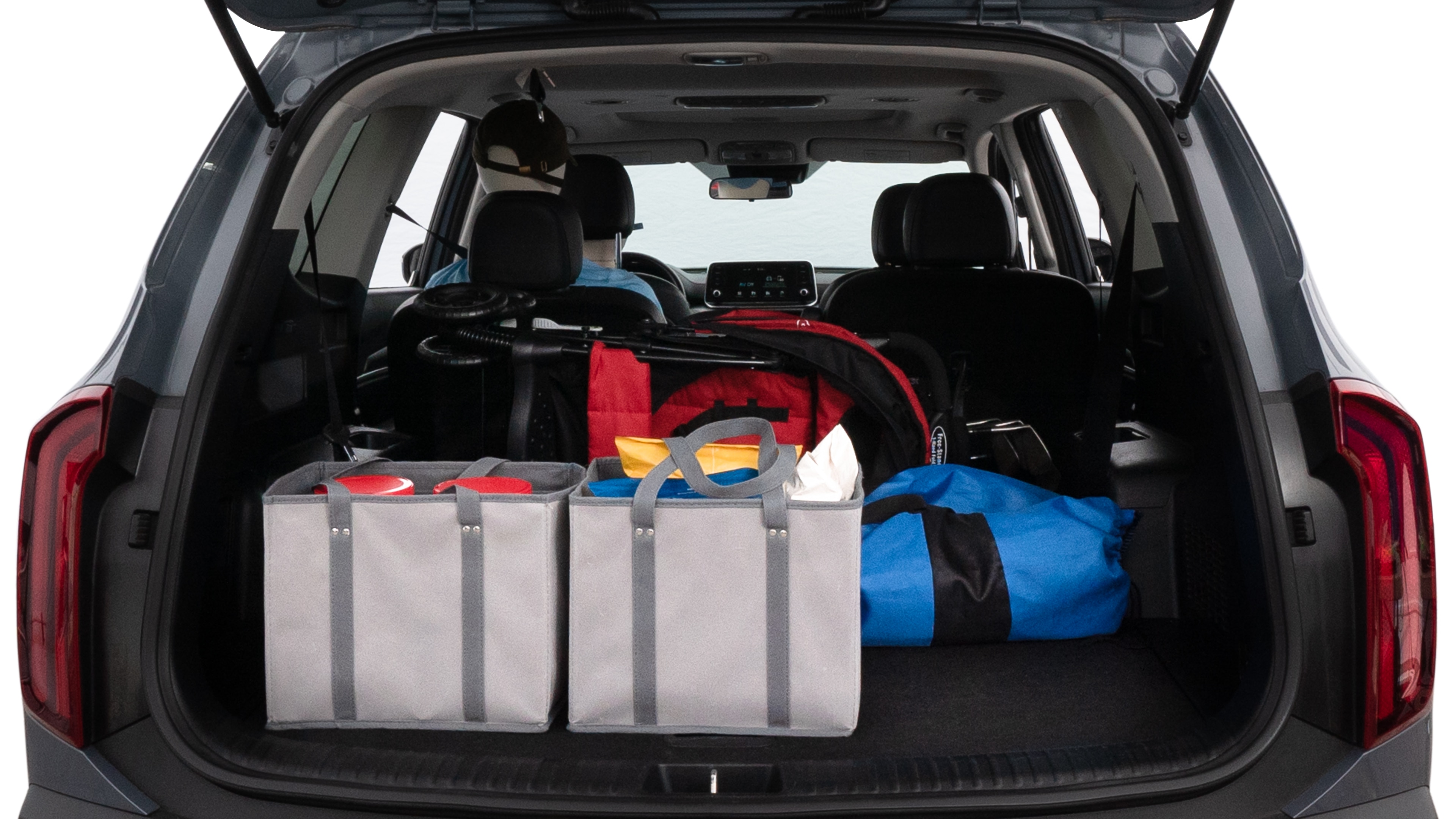 The trunk lid is open showing full view of the trunk. A baby stroller, three grocery carriers, two camping chairs in the carrying bag, and a set of golf clubs are placed inside.