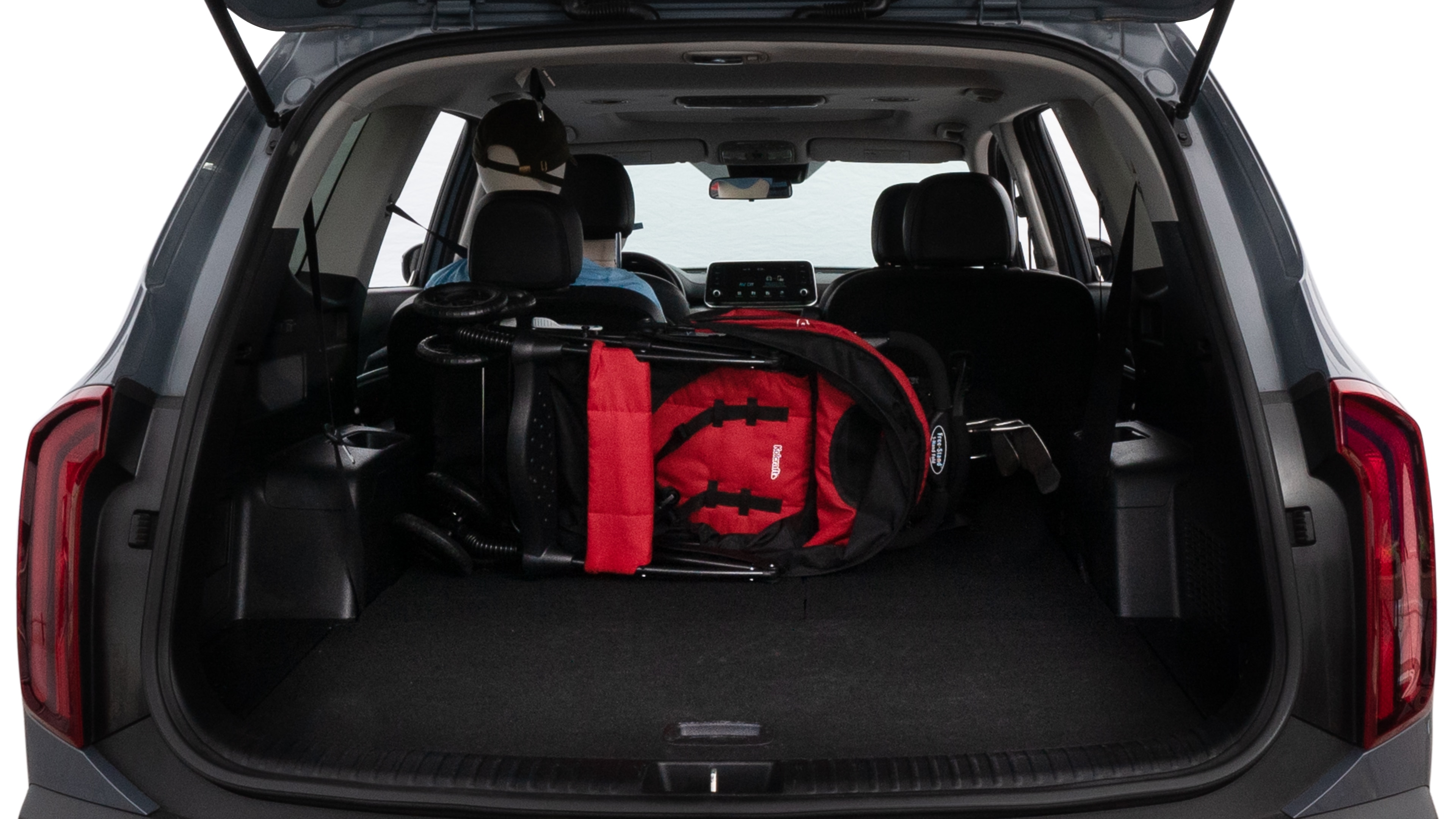 The trunk lid is open showing full view of the trunk. A baby stroller, three grocery carriers, two camping chairs in the carrying bag, and a set of golf clubs are placed inside.