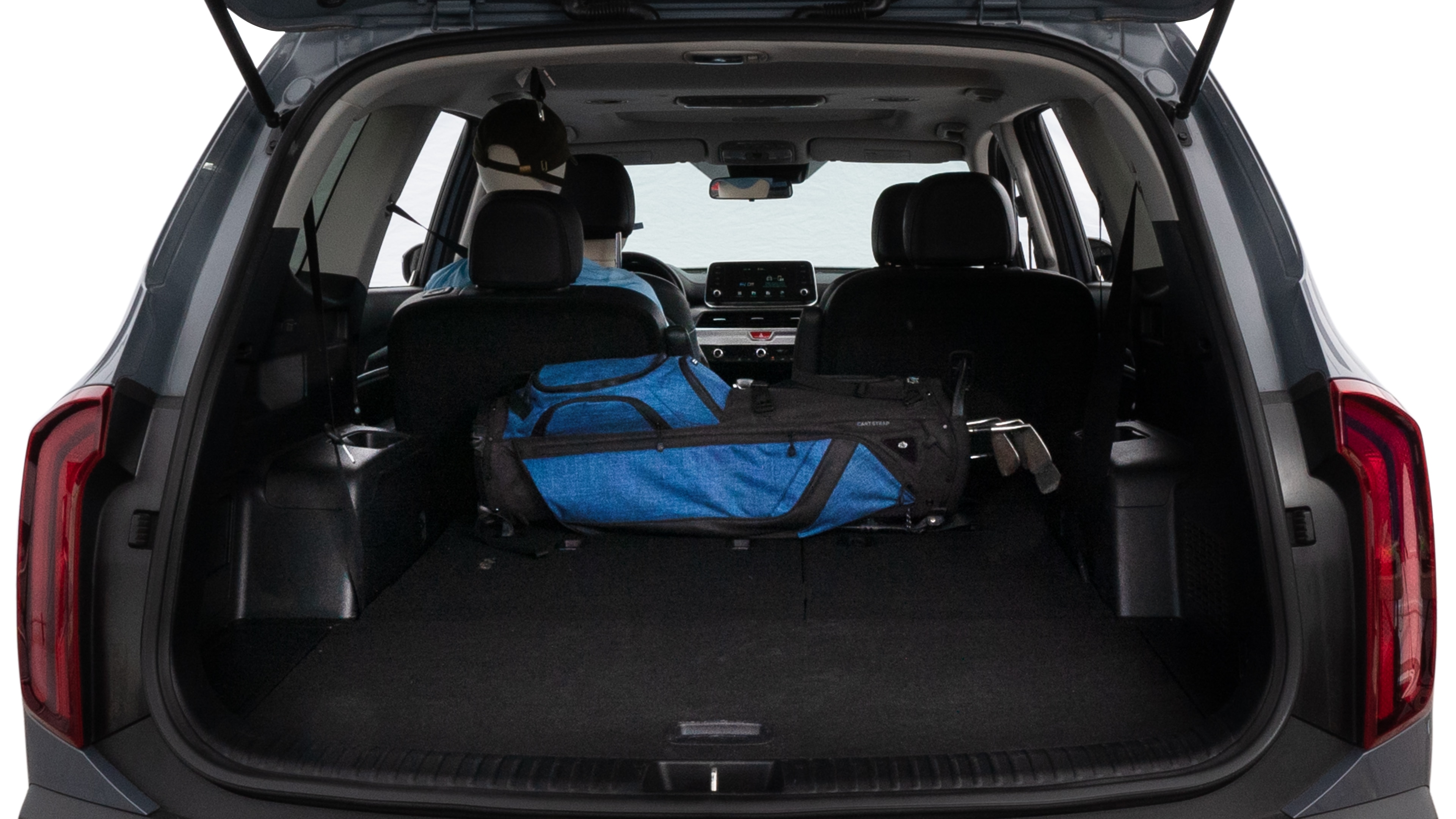 The trunk lid is open showing full view of the trunk. A baby stroller, three grocery carriers, two camping chairs in the carrying bag, and a set of golf clubs are placed inside.