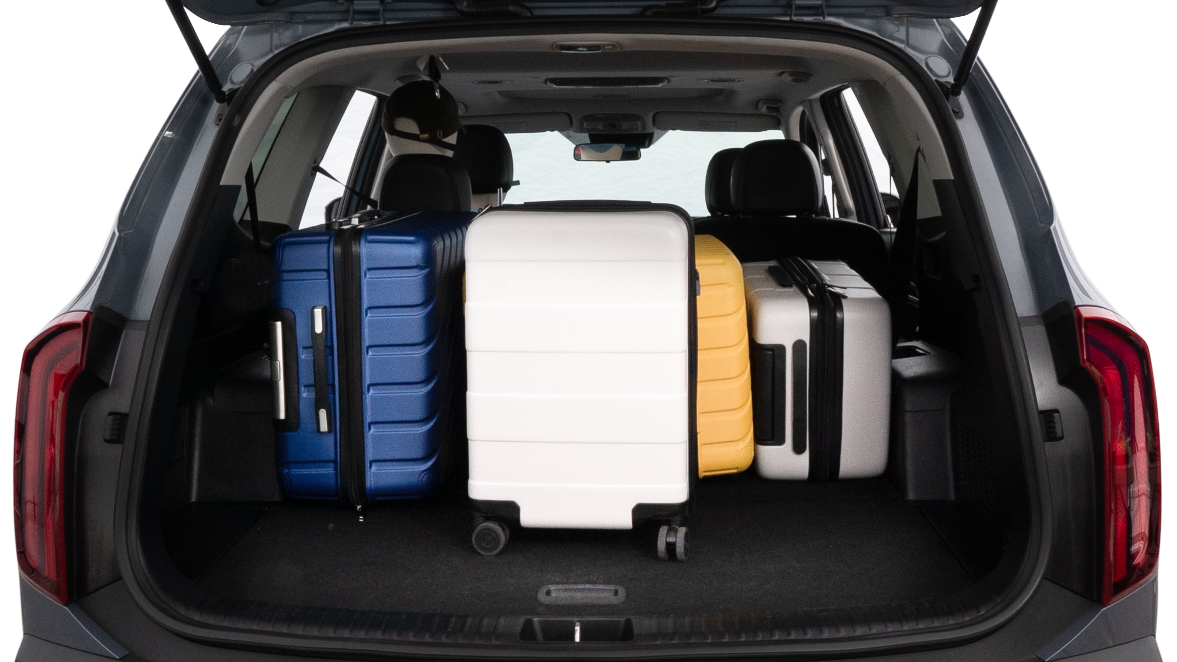 The trunk lid is open, showing full view of the trunk space. One large suitcase, two medium suitcases, and two small suitcases are placed inside.
