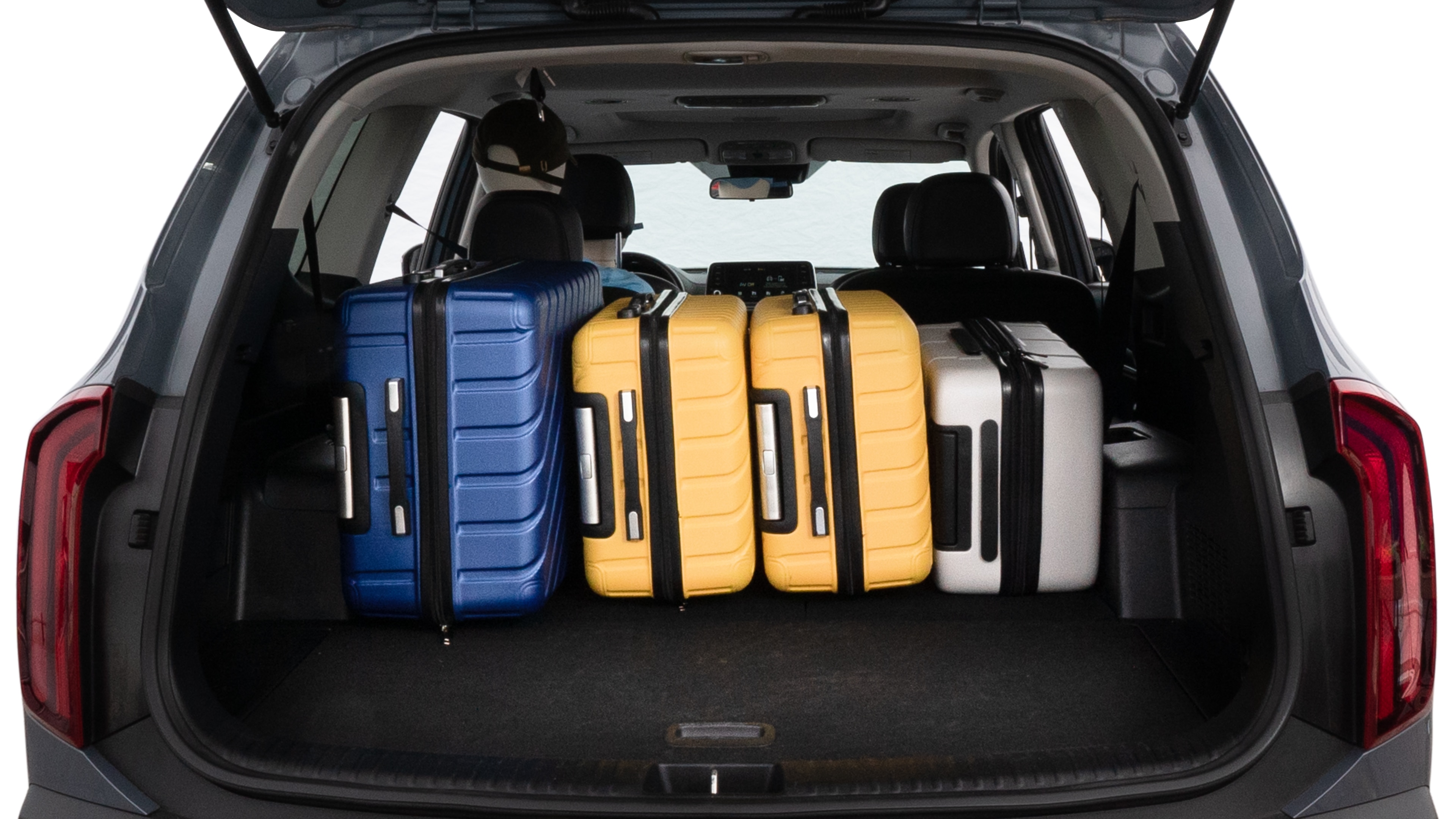 The trunk lid is open, showing full view of the trunk space. One large suitcase, two medium suitcases, and two small suitcases are placed inside.