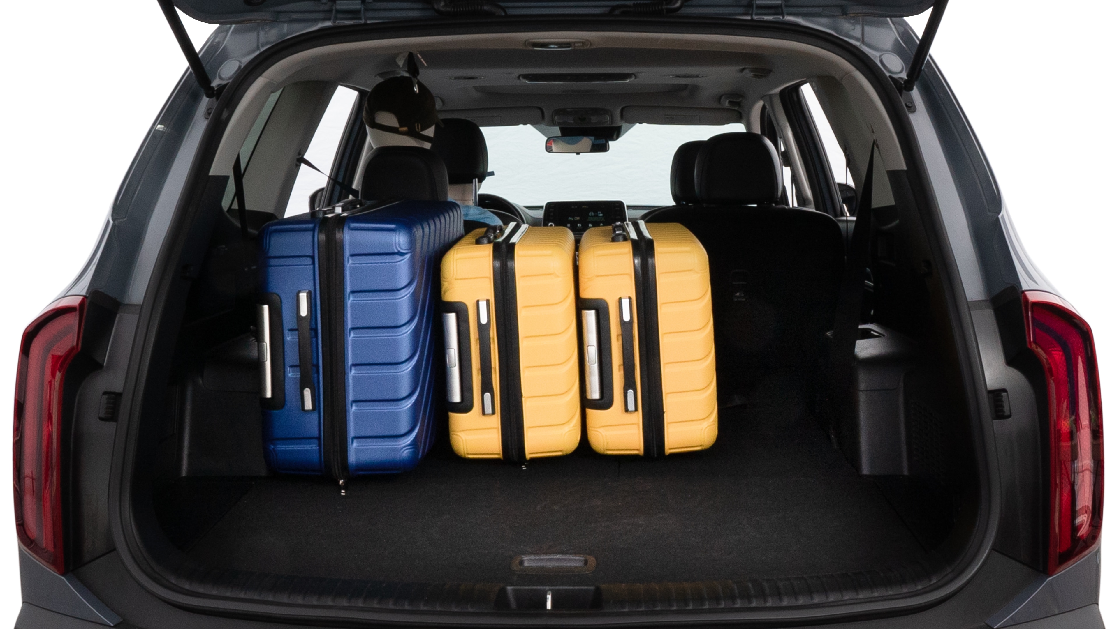 The trunk lid is open, showing full view of the trunk space. One large suitcase, two medium suitcases, and two small suitcases are placed inside.