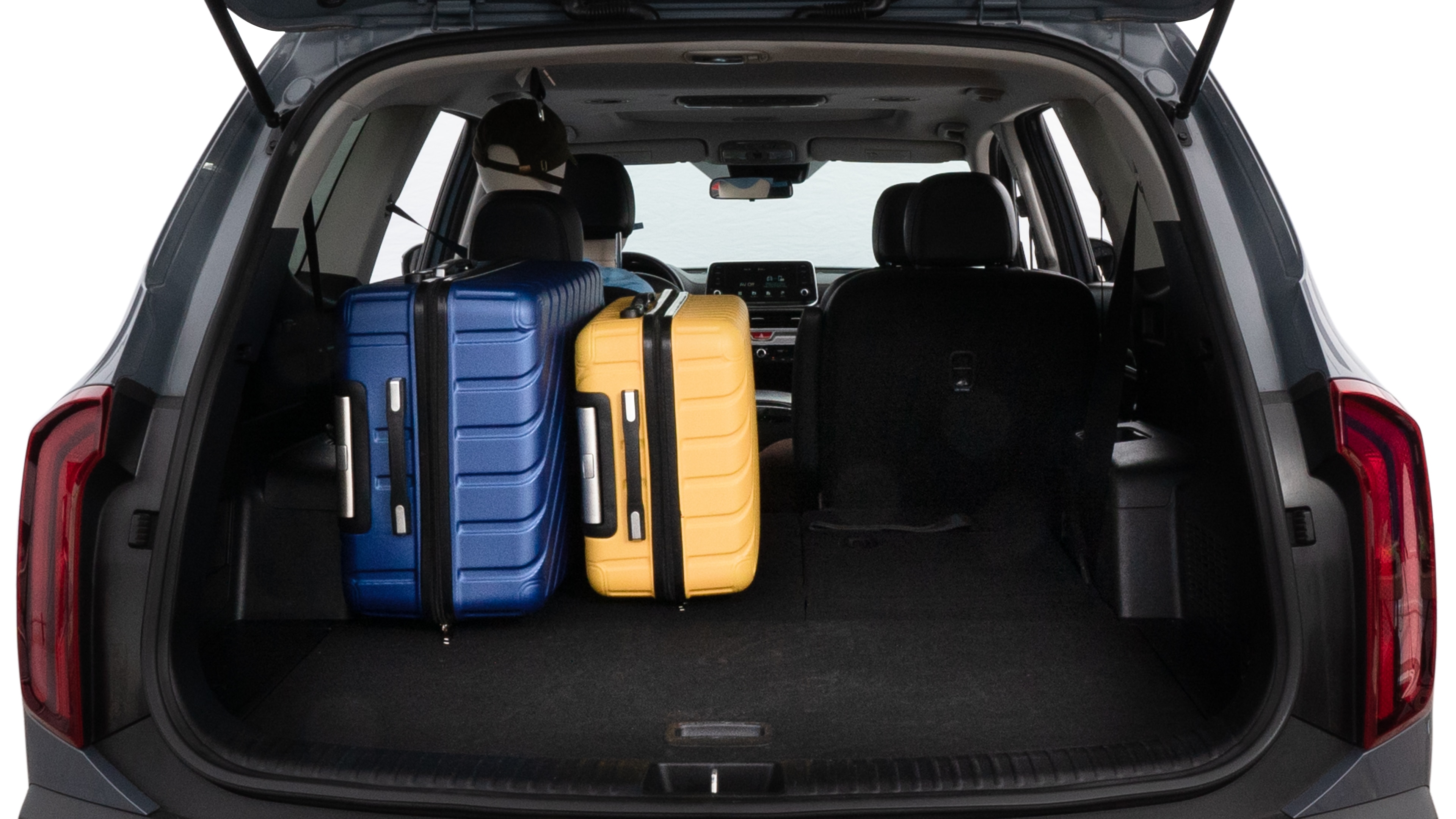 The trunk lid is open, showing full view of the trunk space. One large suitcase, two medium suitcases, and two small suitcases are placed inside.