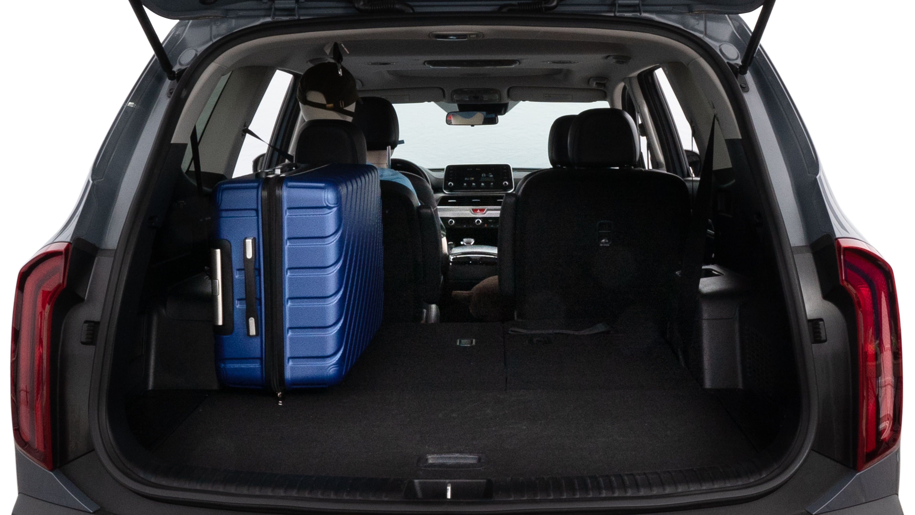 The trunk lid is open, showing full view of the trunk space. One large suitcase, two medium suitcases, and two small suitcases are placed inside.