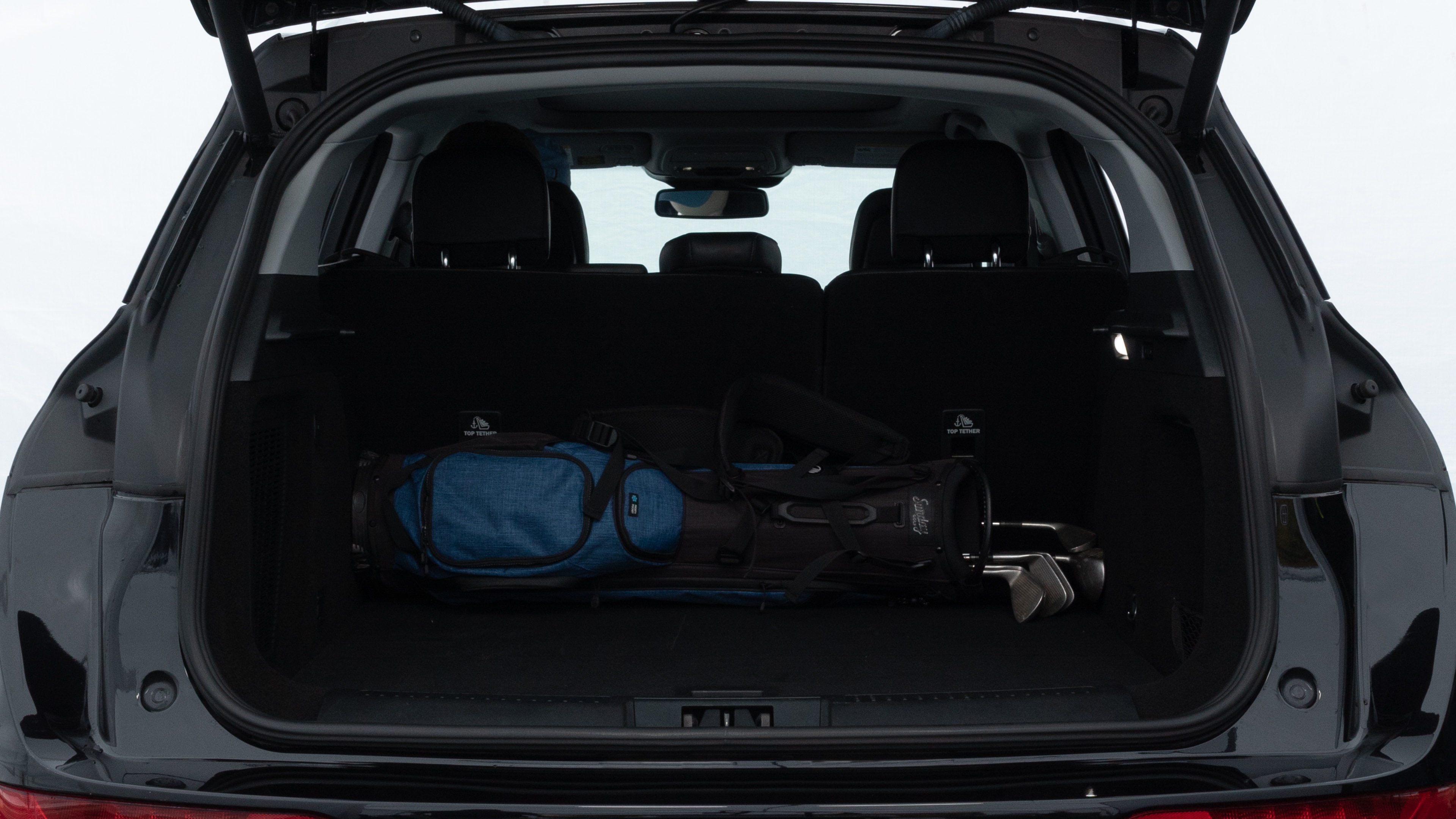 The trunk lid is open showing full view of the trunk. A baby stroller, three grocery carriers, two camping chairs in the carrying bag, and a set of golf clubs are placed inside.