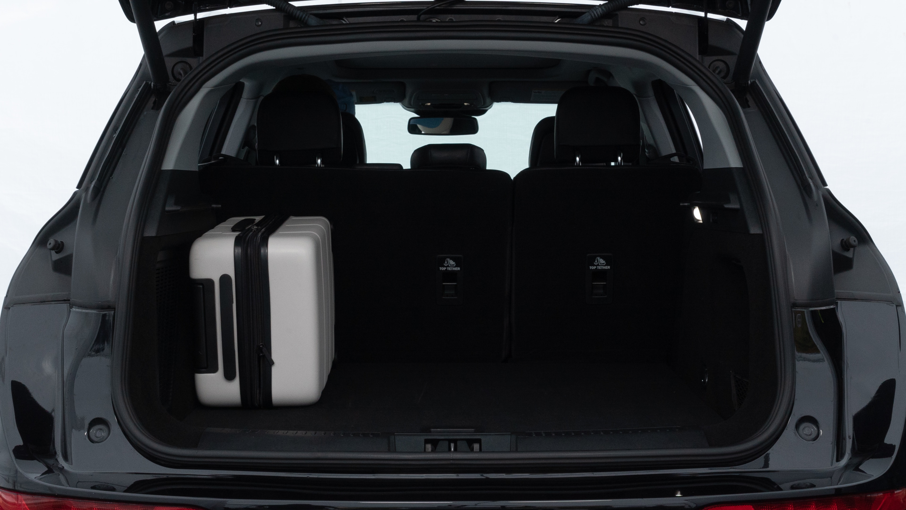 The trunk lid is open, showing full view of the trunk space. Two medium and two small suitcases are placed inside.