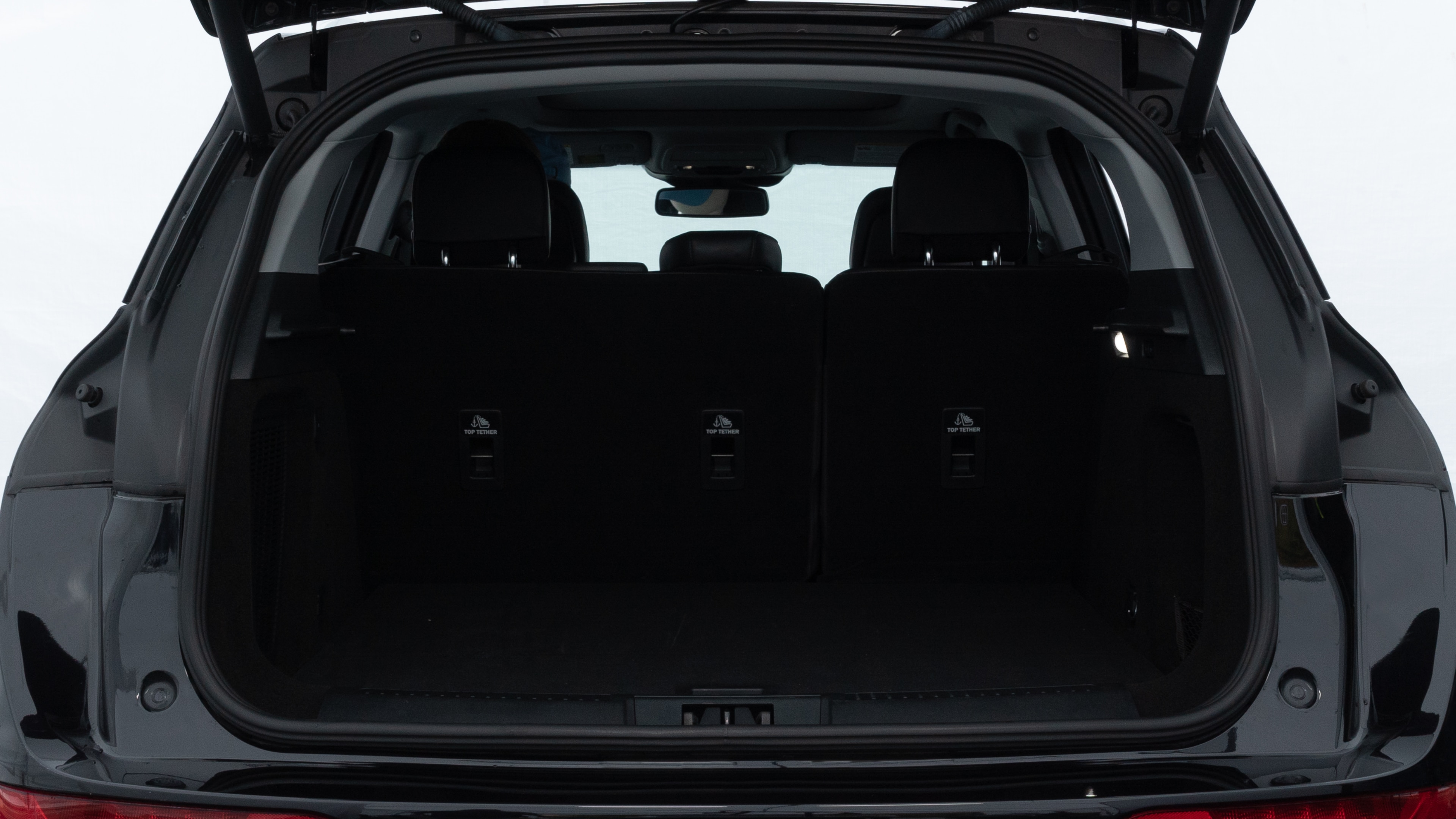 The trunk lid is open, showing full view of the trunk space. Two medium and two small suitcases are placed inside.