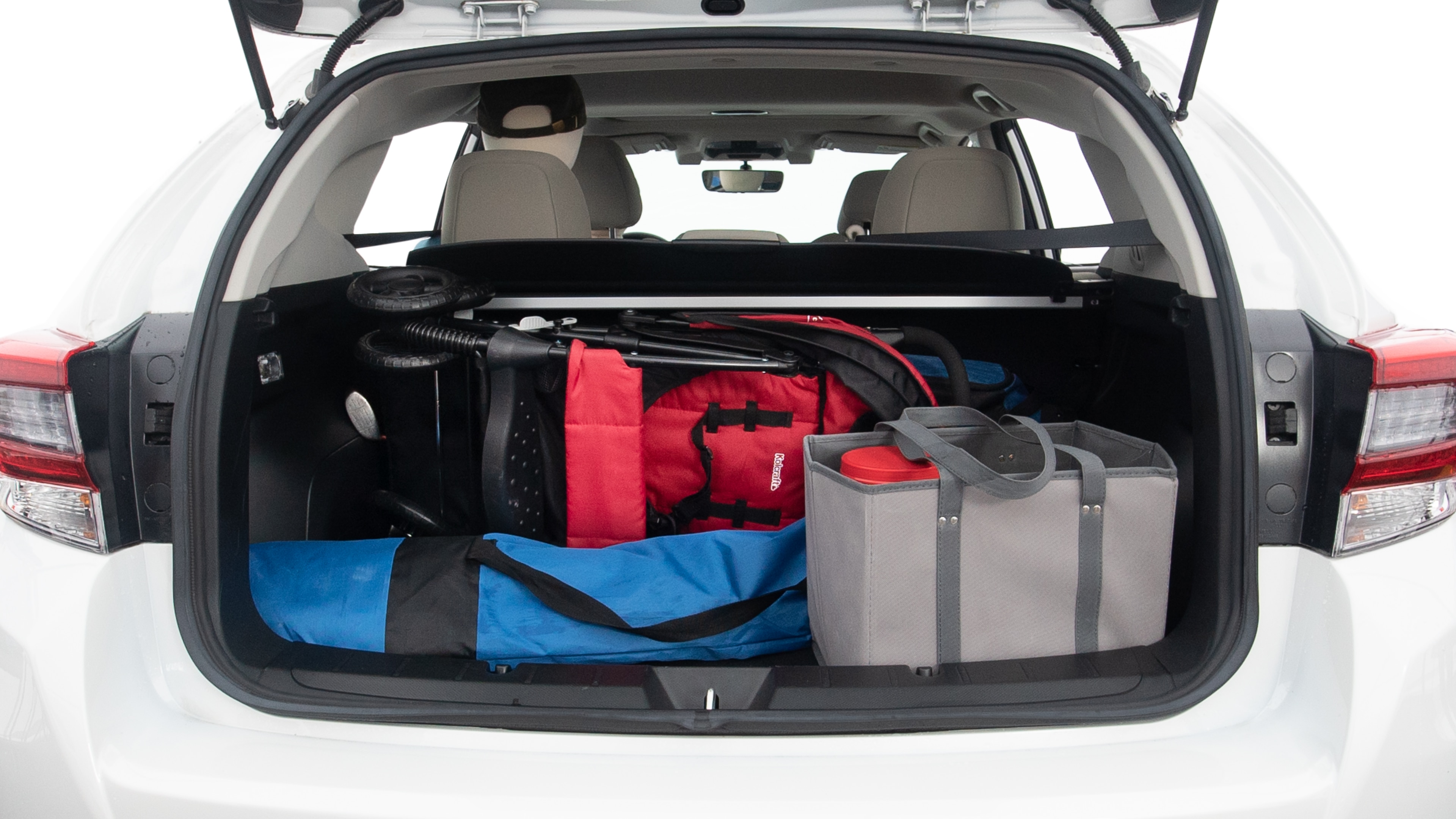 The trunk lid is open showing full view of the trunk. A baby stroller, one grocery carriers, one camping chairs in the carrying bag, and a set of golf clubs are placed inside.