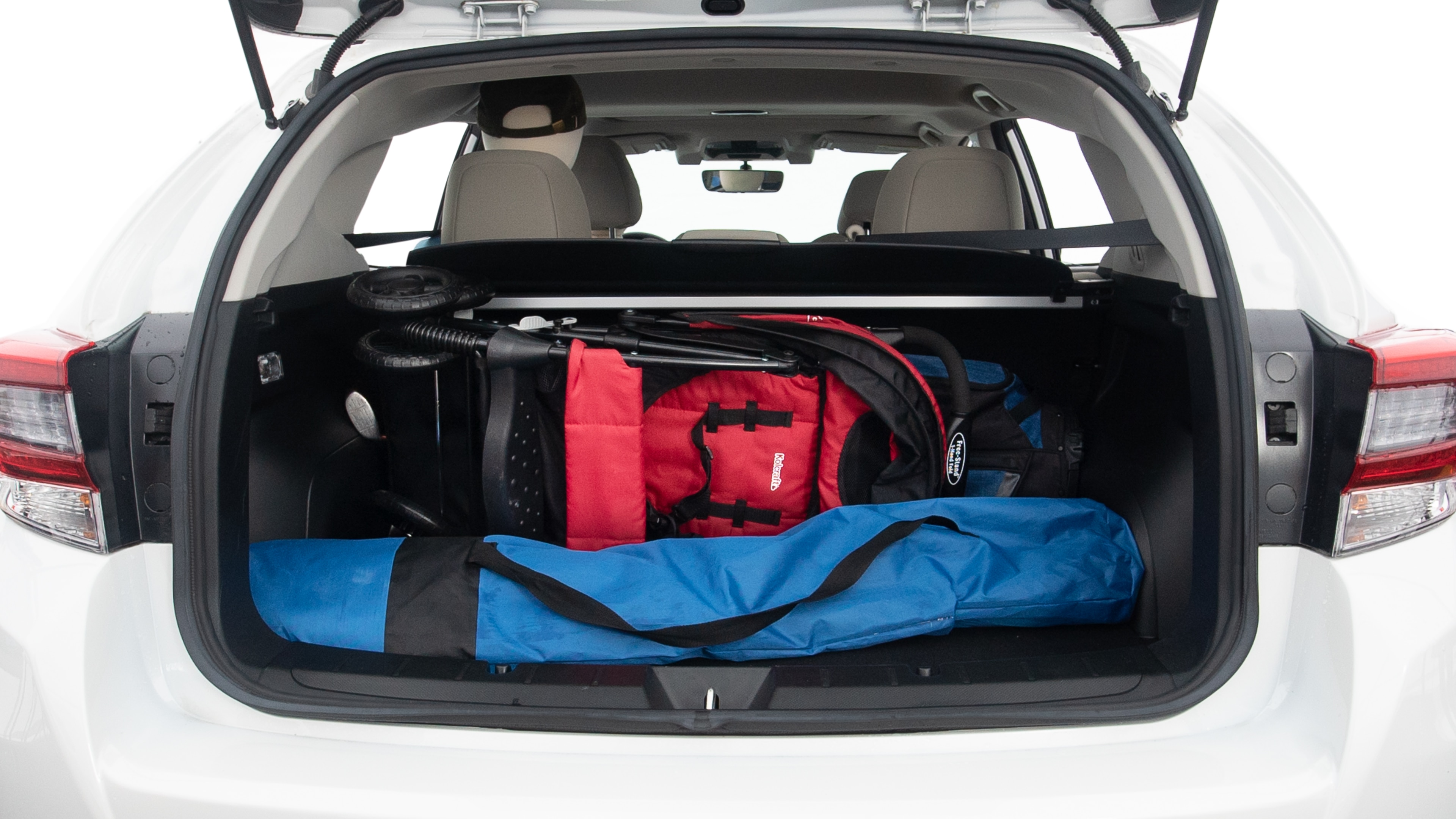 The trunk lid is open showing full view of the trunk. A baby stroller, one grocery carriers, one camping chairs in the carrying bag, and a set of golf clubs are placed inside.