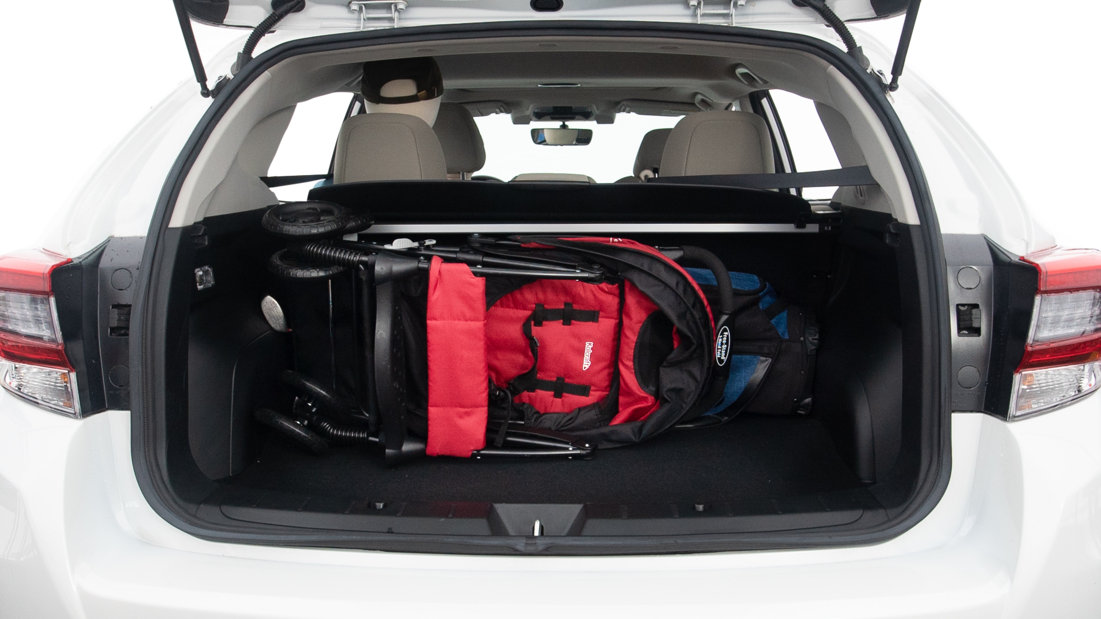 The trunk lid is open showing full view of the trunk. A baby stroller, one grocery carriers, one camping chairs in the carrying bag, and a set of golf clubs are placed inside.