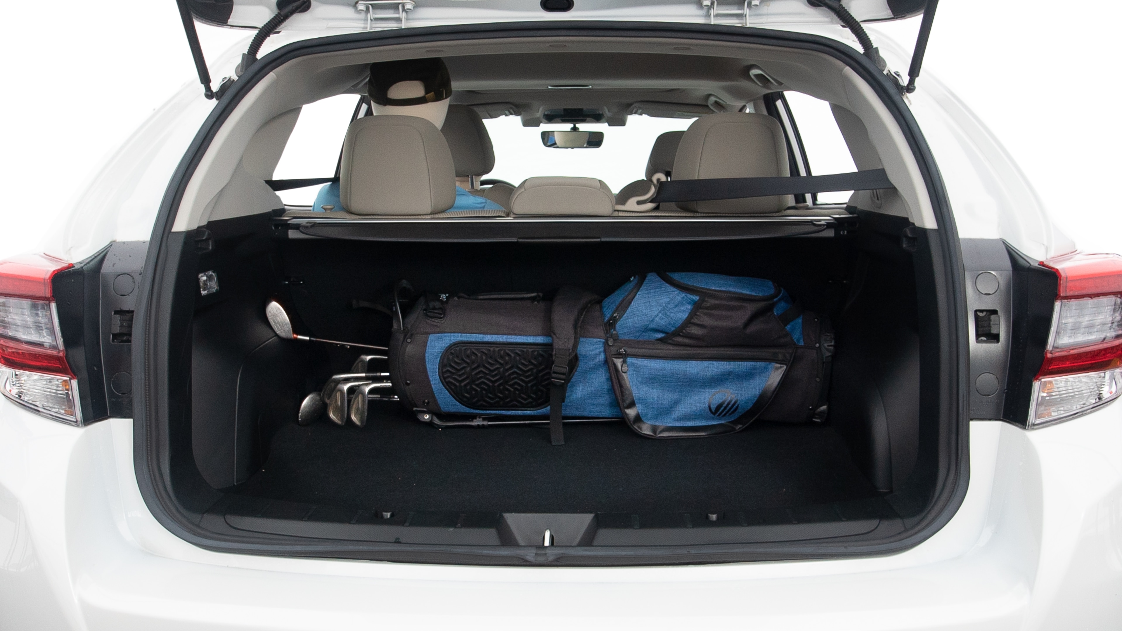 The trunk lid is open showing full view of the trunk. A baby stroller, one grocery carriers, one camping chairs in the carrying bag, and a set of golf clubs are placed inside.