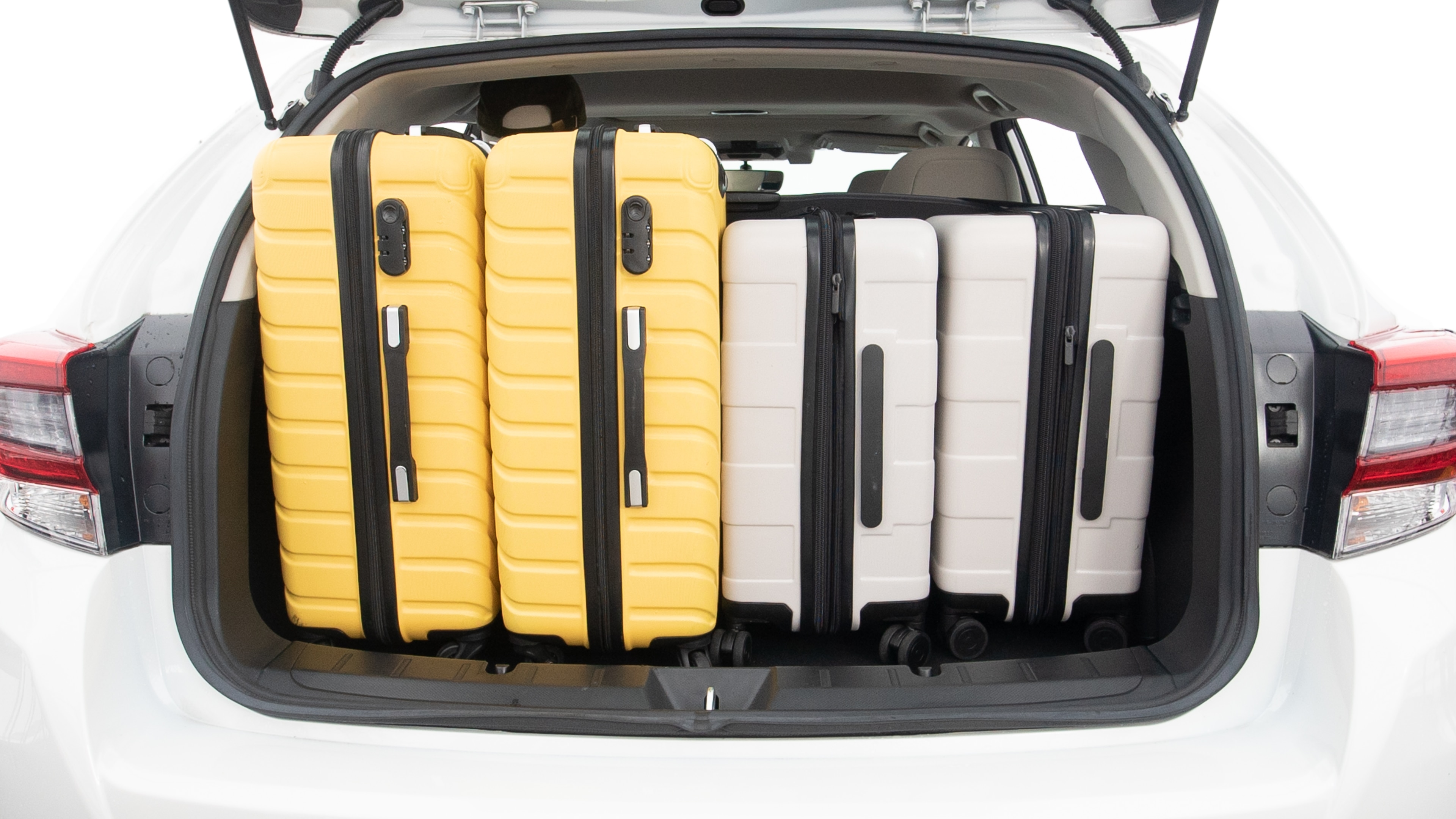 The trunk lid is open, showing full view of the trunk space. Two large and two small suitcases are placed inside.