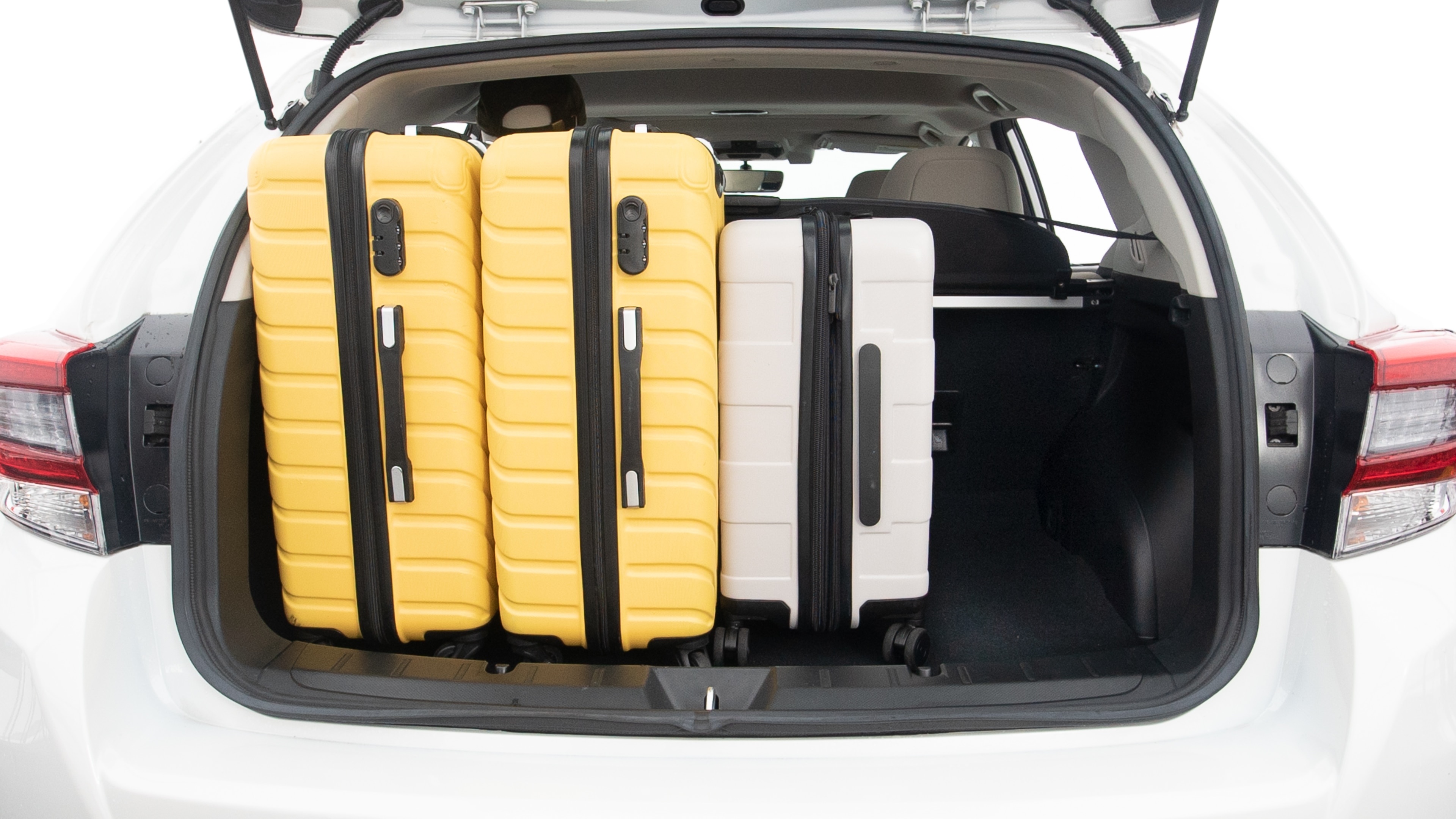 The trunk lid is open, showing full view of the trunk space. Two large and two small suitcases are placed inside.