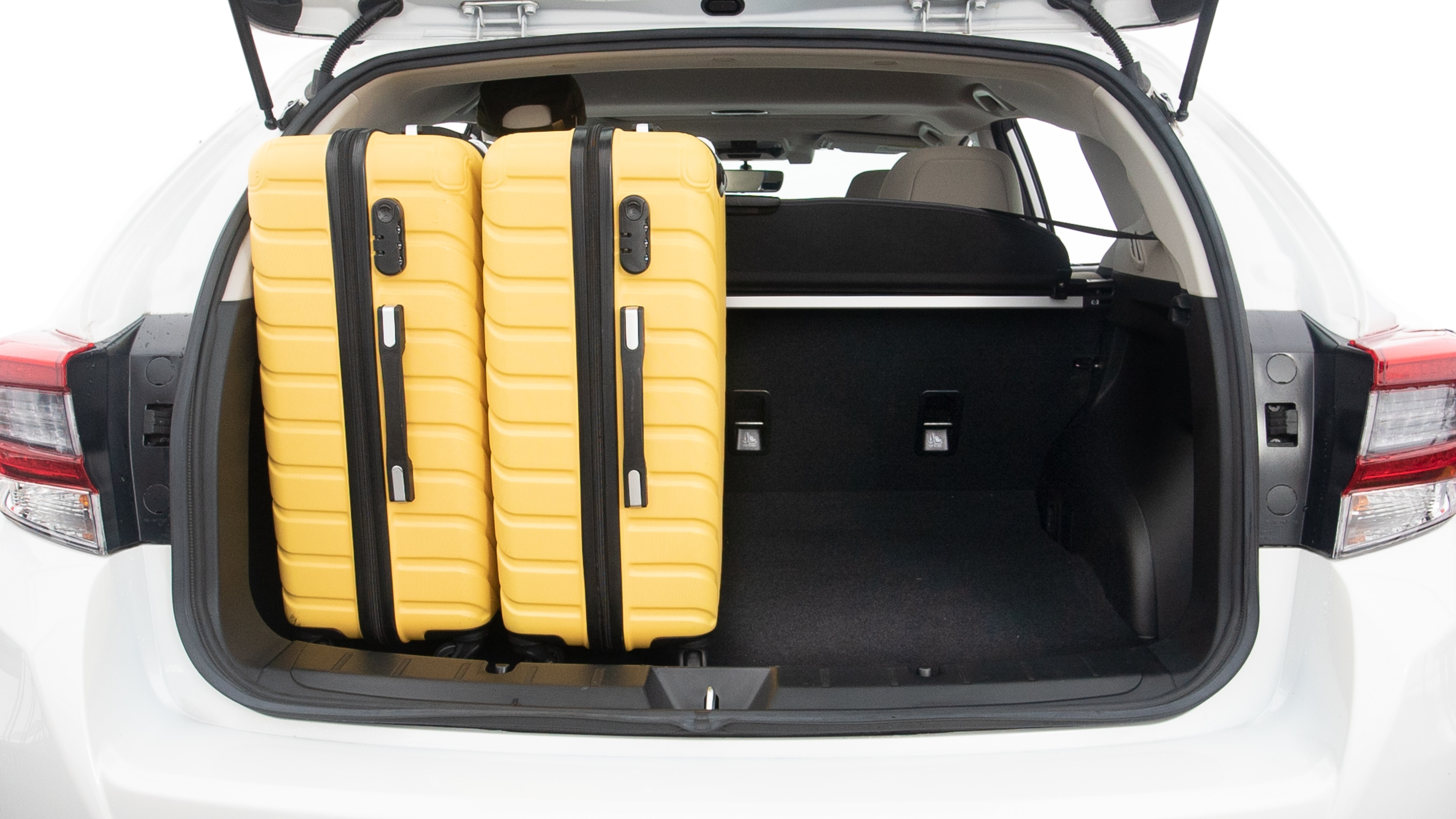 The trunk lid is open, showing full view of the trunk space. Two large and two small suitcases are placed inside.