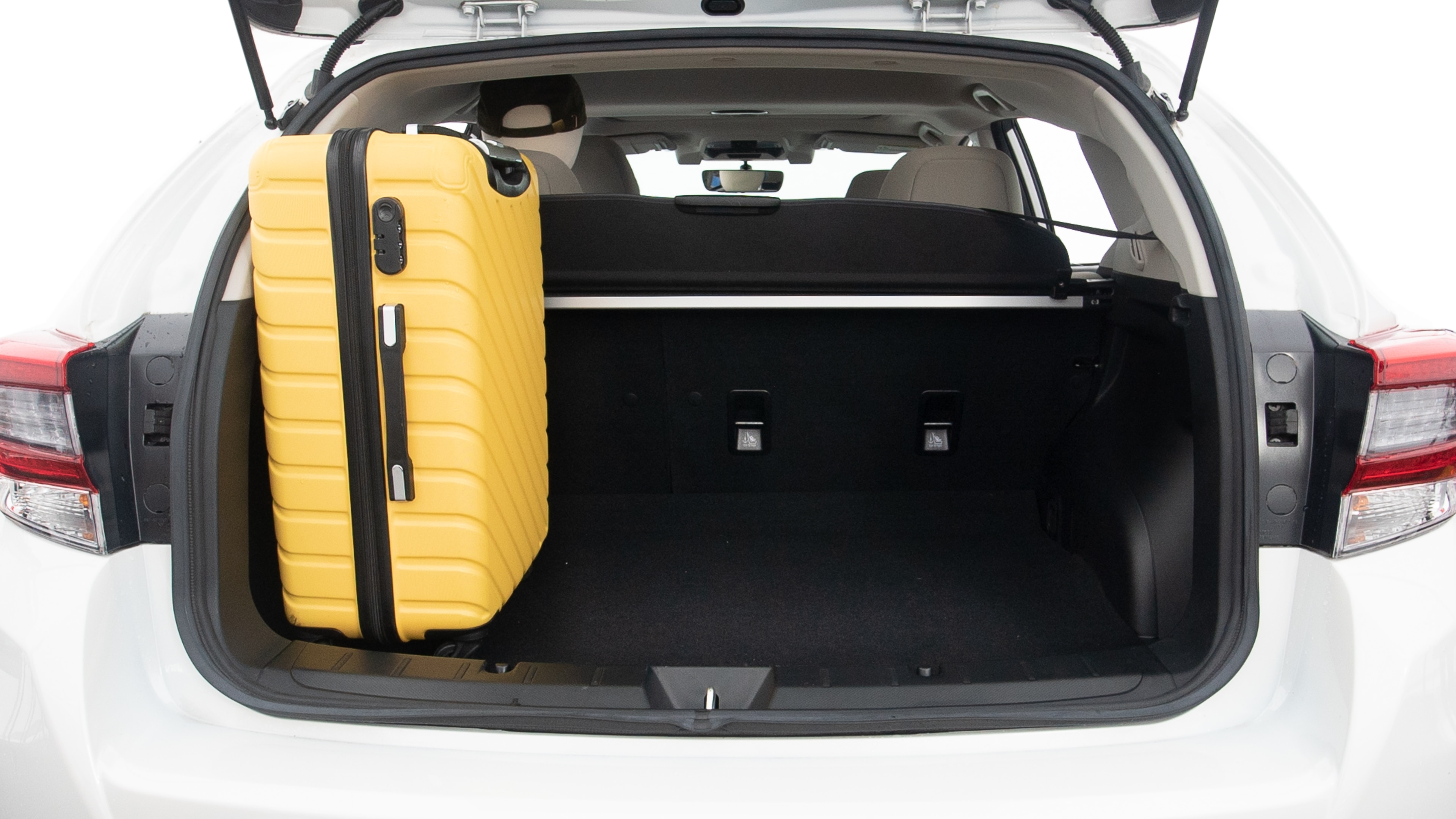 The trunk lid is open, showing full view of the trunk space. Two large and two small suitcases are placed inside.
