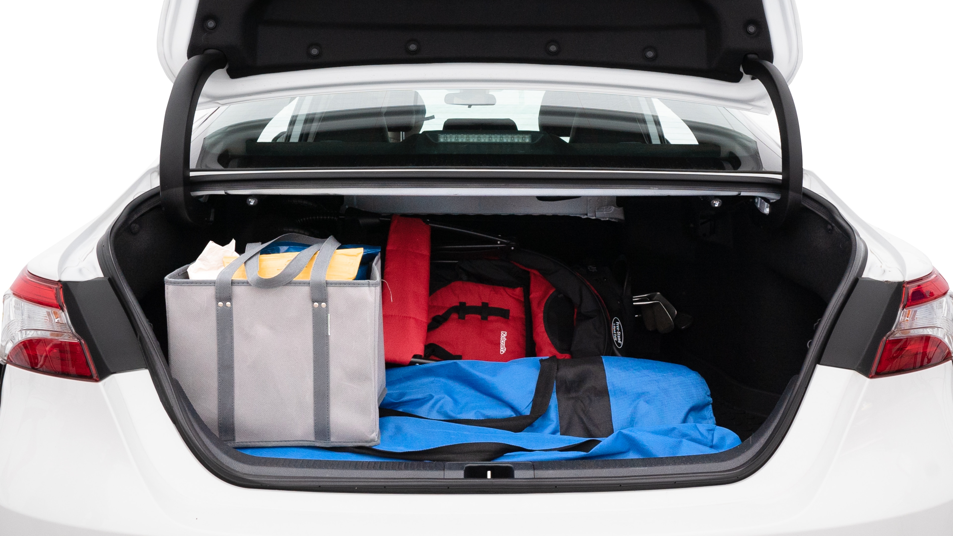 The trunk lid is open showing full view of the trunk. A baby stroller, three grocery carriers, two camping chairs in the carrying bag, and a set of golf clubs are placed inside.