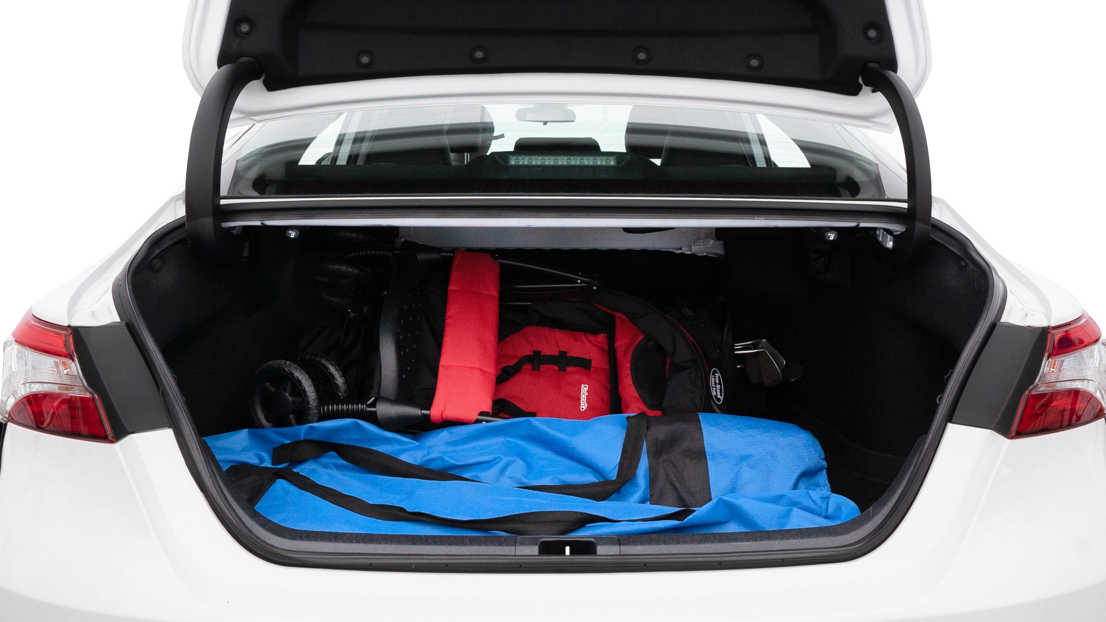The trunk lid is open showing full view of the trunk. A baby stroller, three grocery carriers, two camping chairs in the carrying bag, and a set of golf clubs are placed inside.