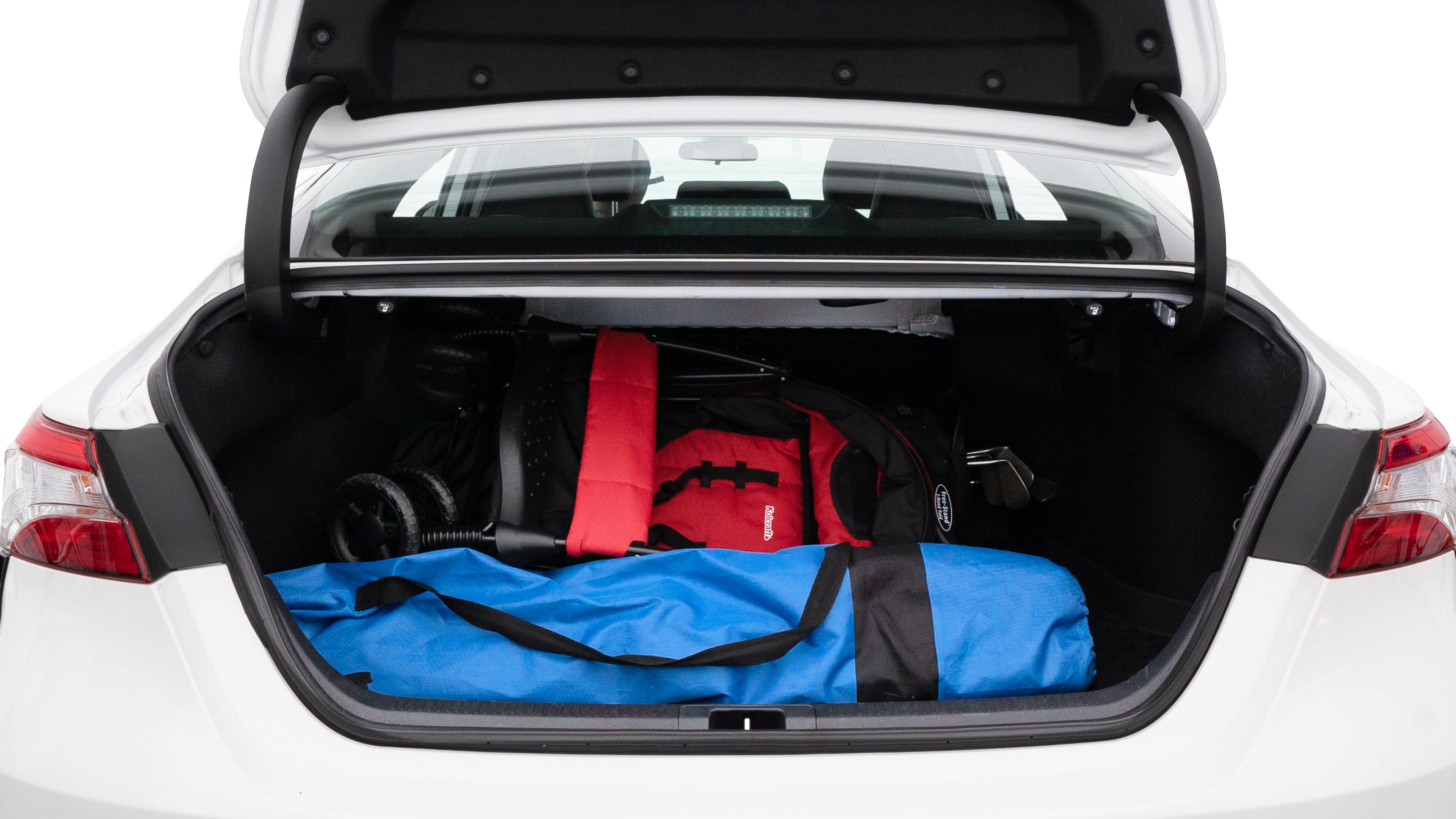 The trunk lid is open showing full view of the trunk. A baby stroller, three grocery carriers, two camping chairs in the carrying bag, and a set of golf clubs are placed inside.