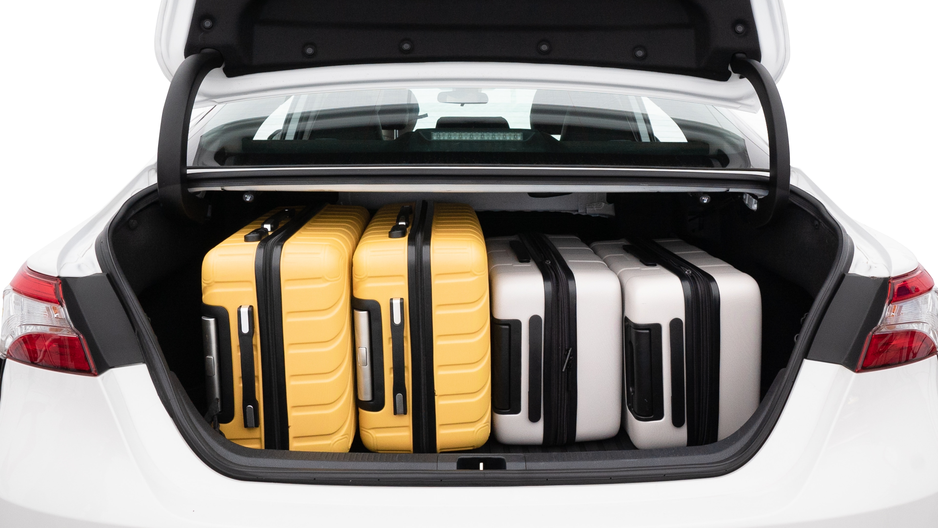 The trunk lid is open, showing full view of the trunk space. Two medium and two small suitcases are placed inside.