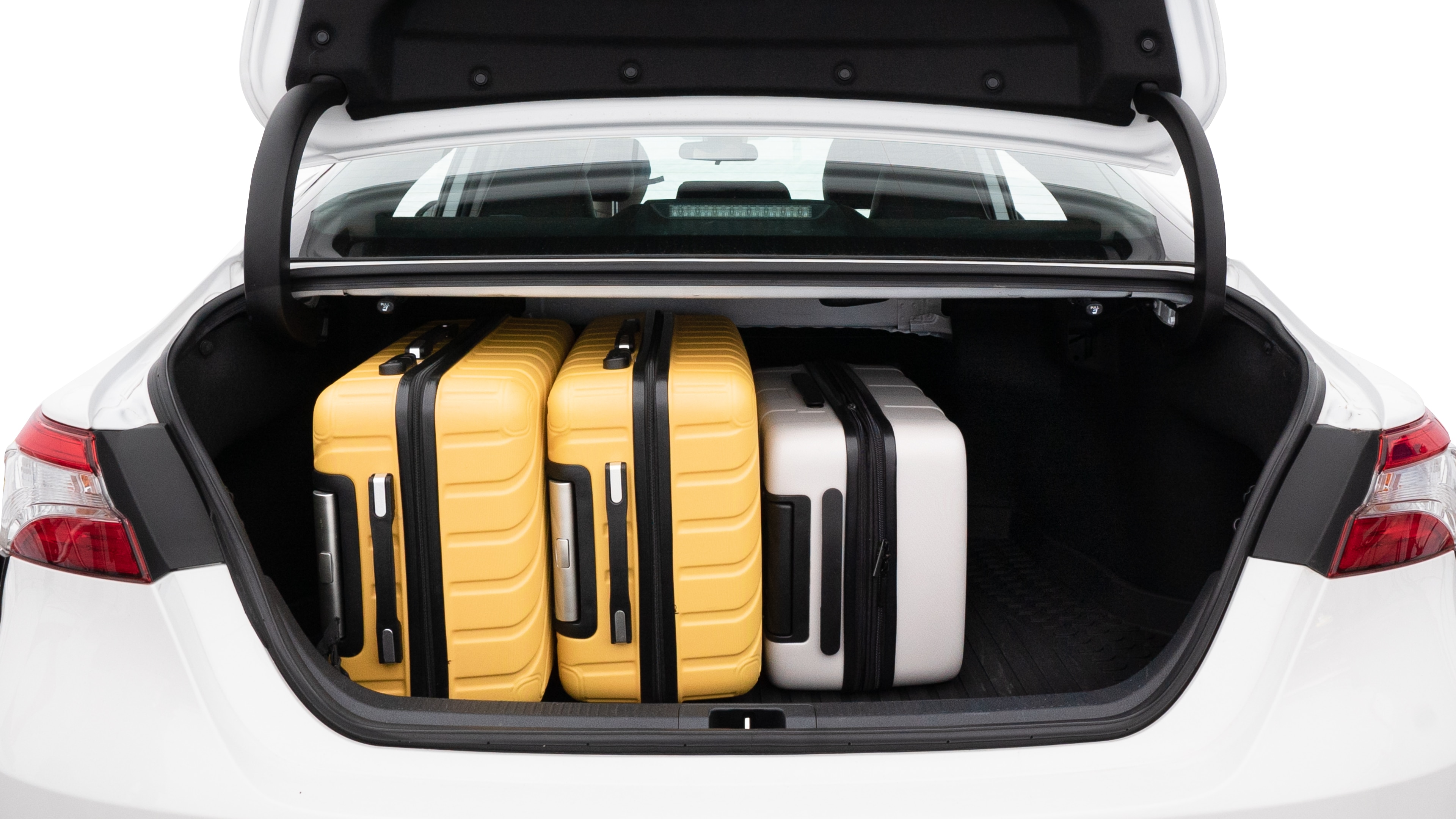 The trunk lid is open, showing full view of the trunk space. Two medium and two small suitcases are placed inside.