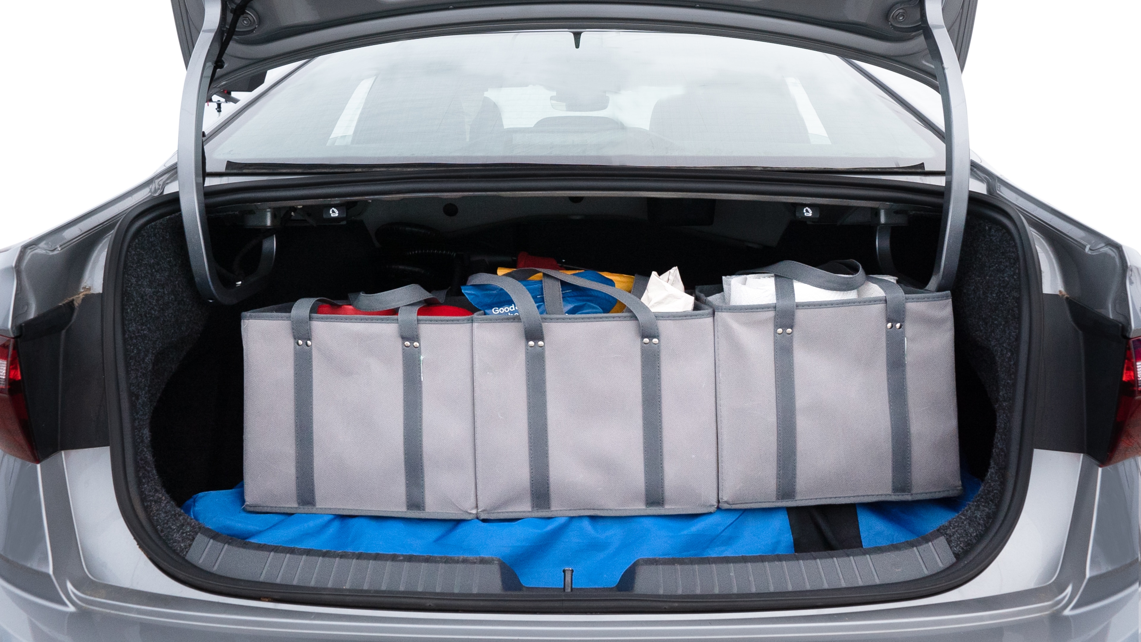 The trunk lid is open showing full view of the trunk. A baby stroller, three grocery carriers, two camping chairs in the carrying bag, and a set of golf clubs are placed inside.