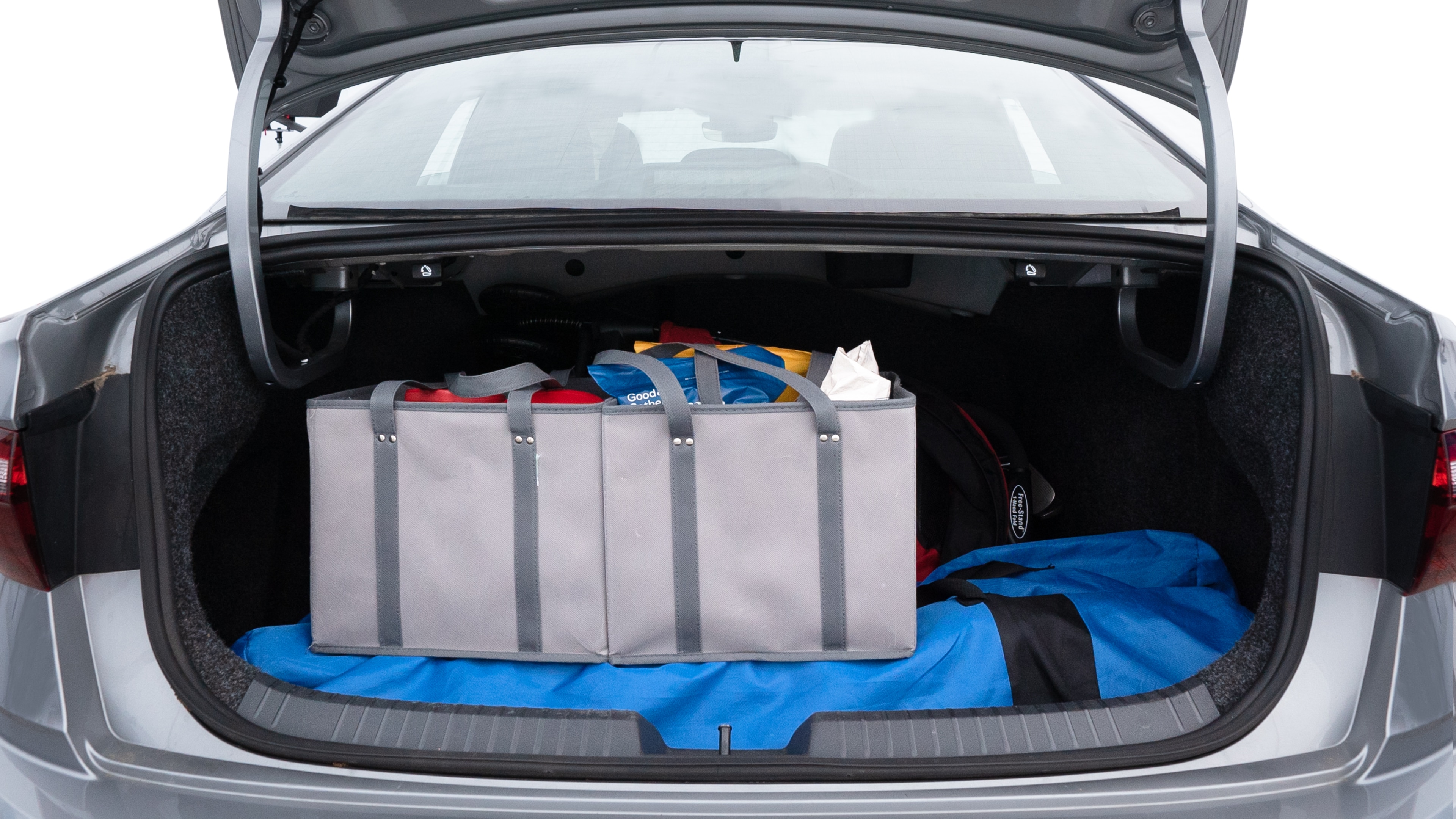 The trunk lid is open showing full view of the trunk. A baby stroller, three grocery carriers, two camping chairs in the carrying bag, and a set of golf clubs are placed inside.