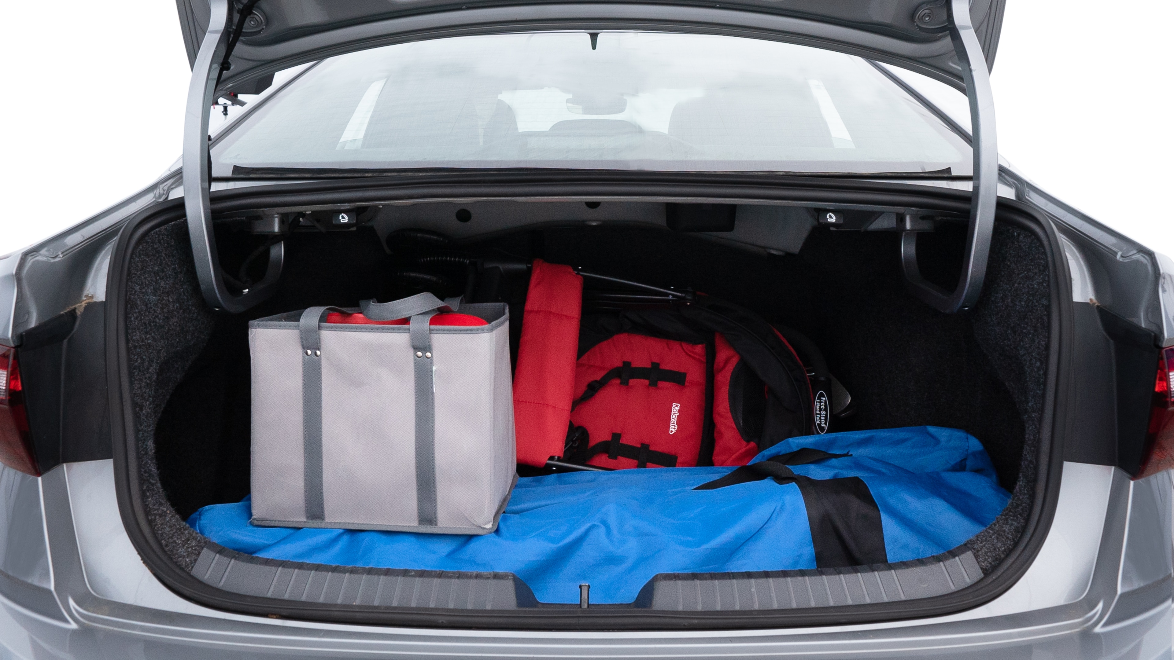 The trunk lid is open showing full view of the trunk. A baby stroller, three grocery carriers, two camping chairs in the carrying bag, and a set of golf clubs are placed inside.