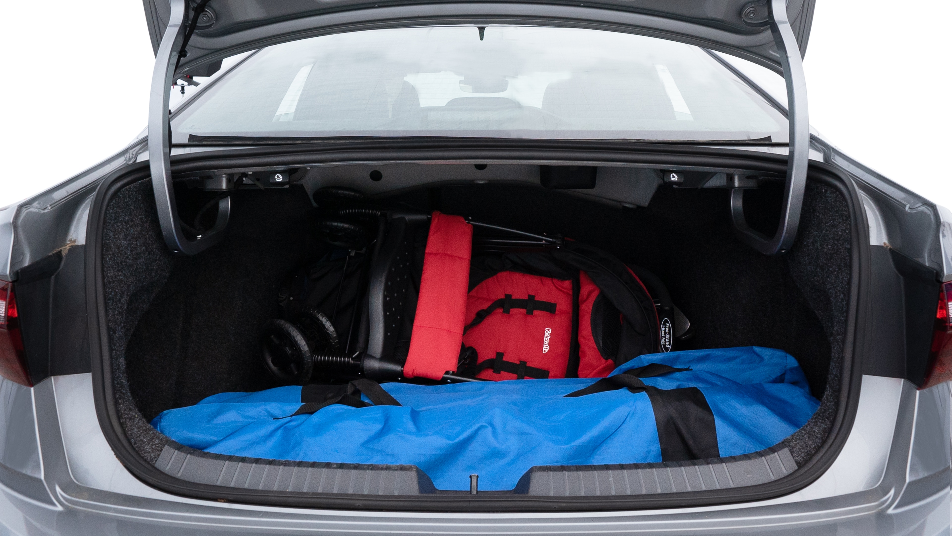 The trunk lid is open showing full view of the trunk. A baby stroller, three grocery carriers, two camping chairs in the carrying bag, and a set of golf clubs are placed inside.