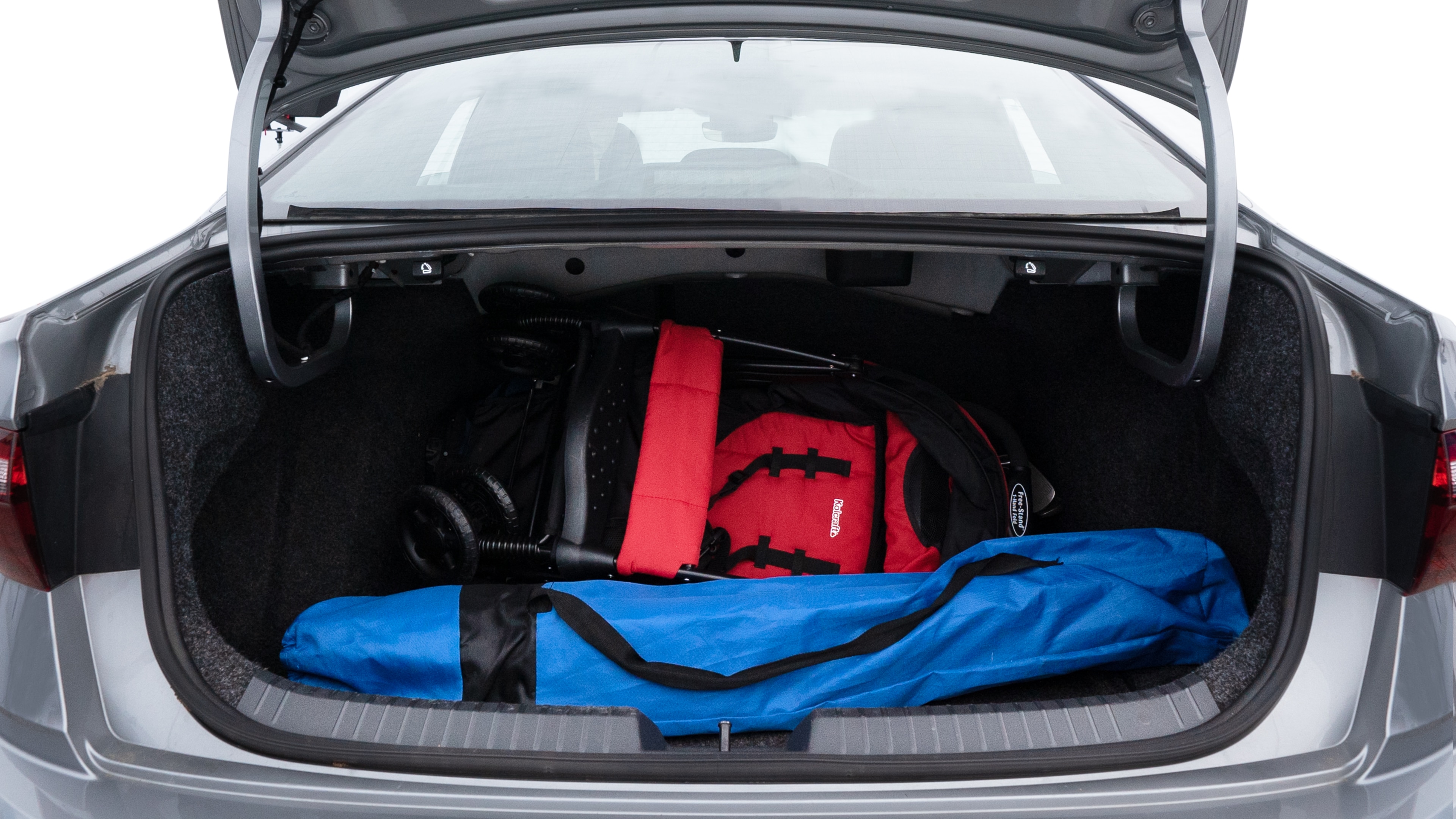 The trunk lid is open showing full view of the trunk. A baby stroller, three grocery carriers, two camping chairs in the carrying bag, and a set of golf clubs are placed inside.