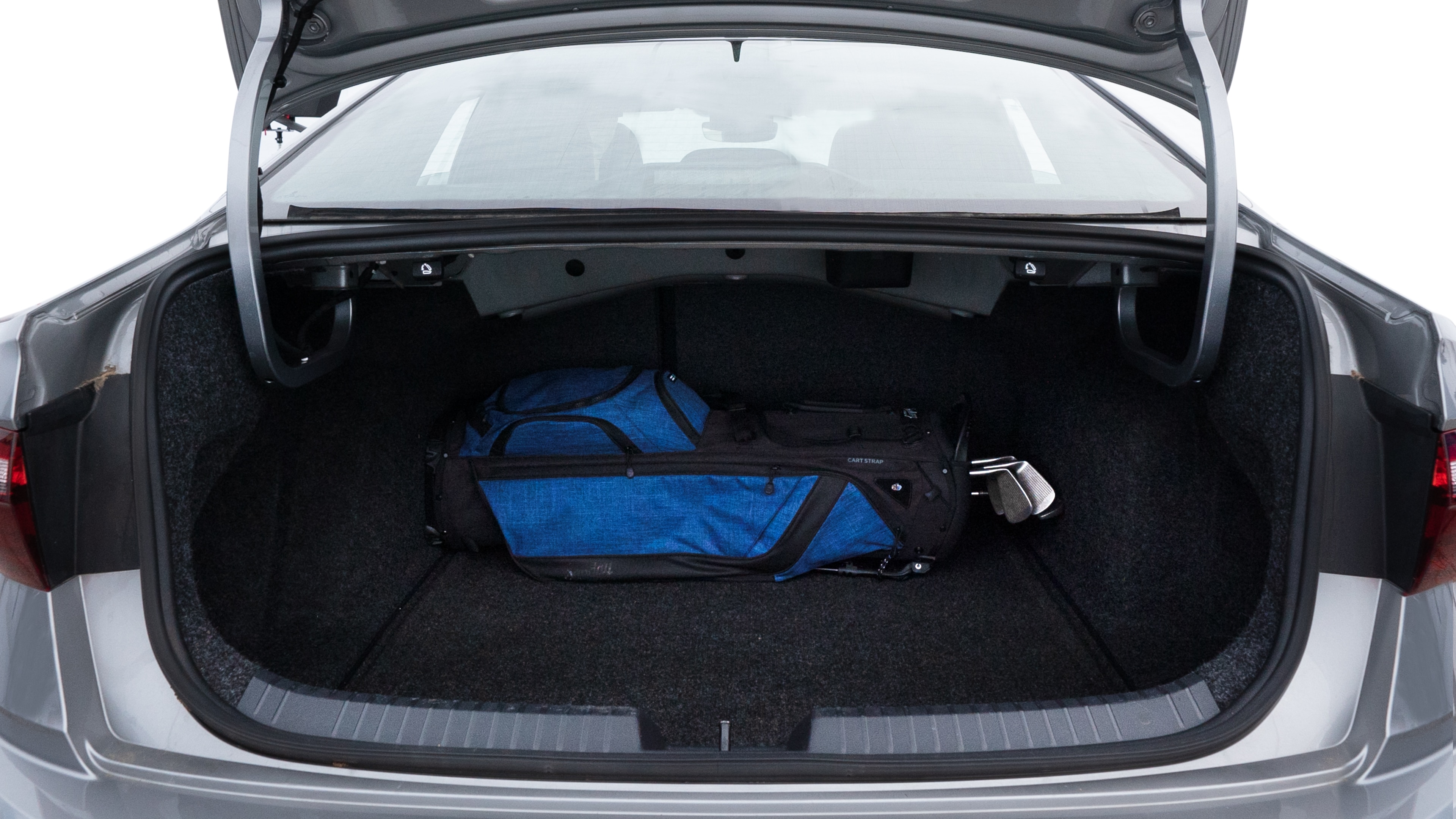 The trunk lid is open showing full view of the trunk. A baby stroller, three grocery carriers, two camping chairs in the carrying bag, and a set of golf clubs are placed inside.