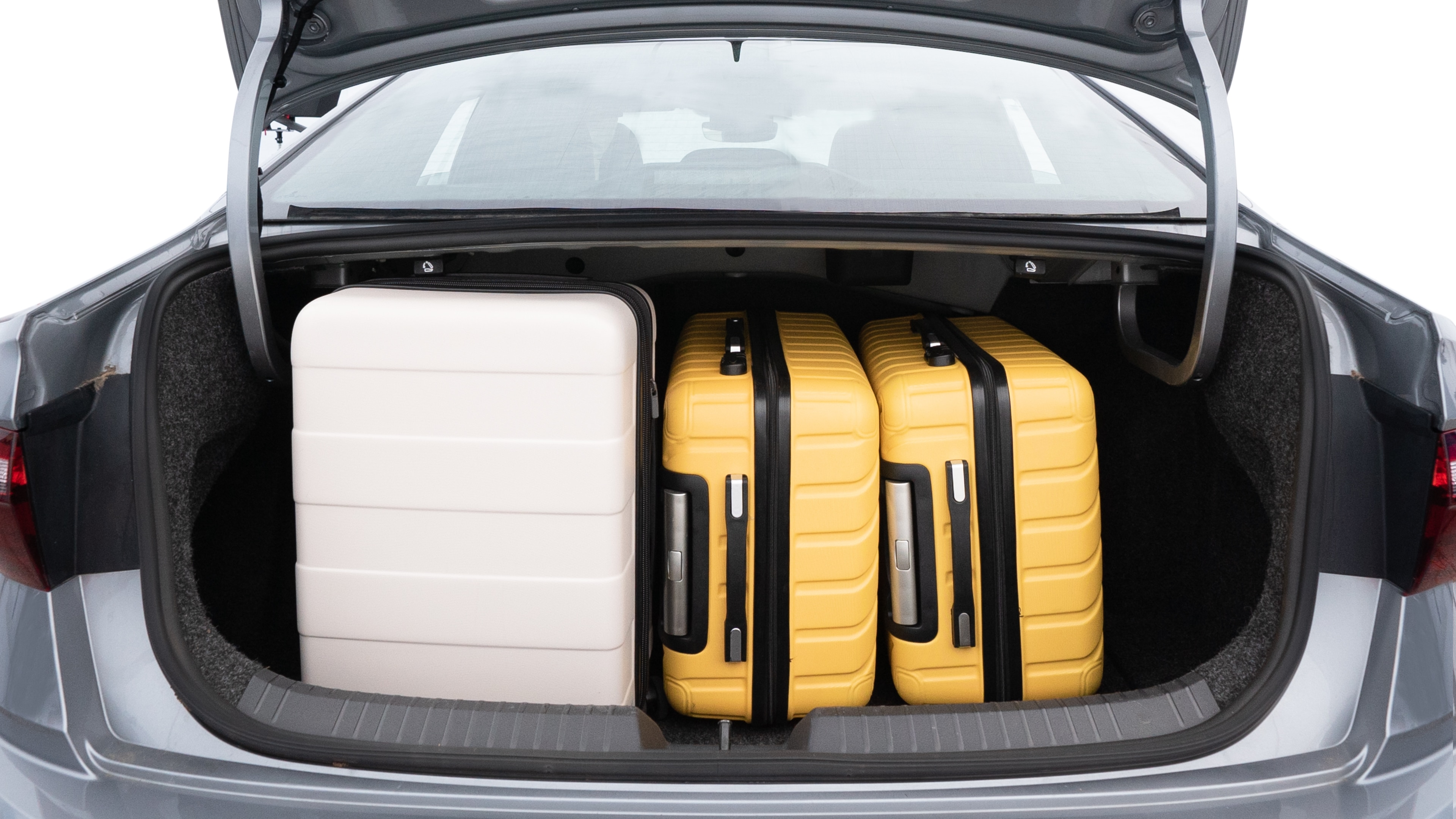 The trunk lid is open, showing full view of the trunk space. Two medium and two small suitcases are placed inside.