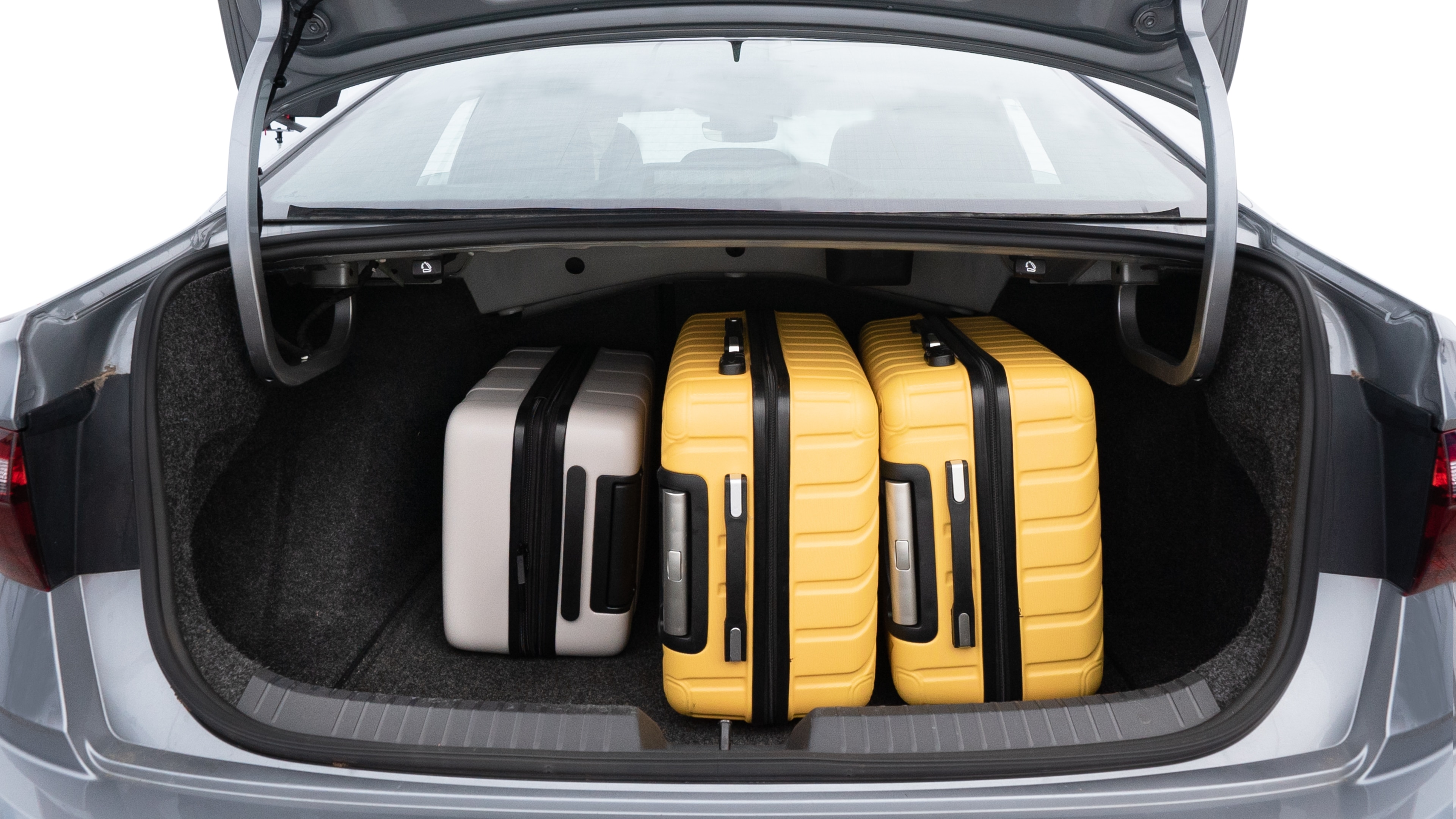 The trunk lid is open, showing full view of the trunk space. Two medium and two small suitcases are placed inside.