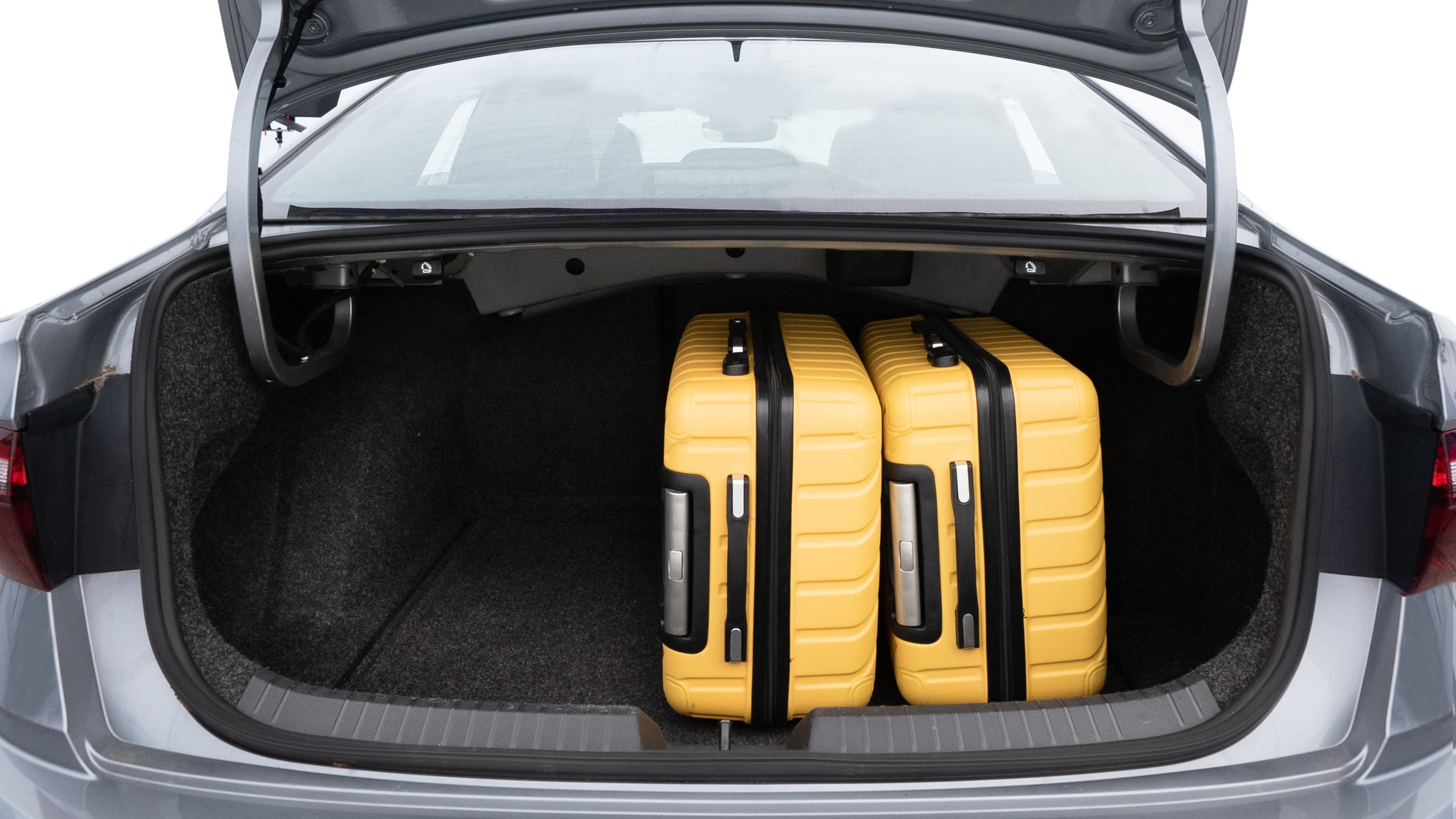 The trunk lid is open, showing full view of the trunk space. Two medium and two small suitcases are placed inside.