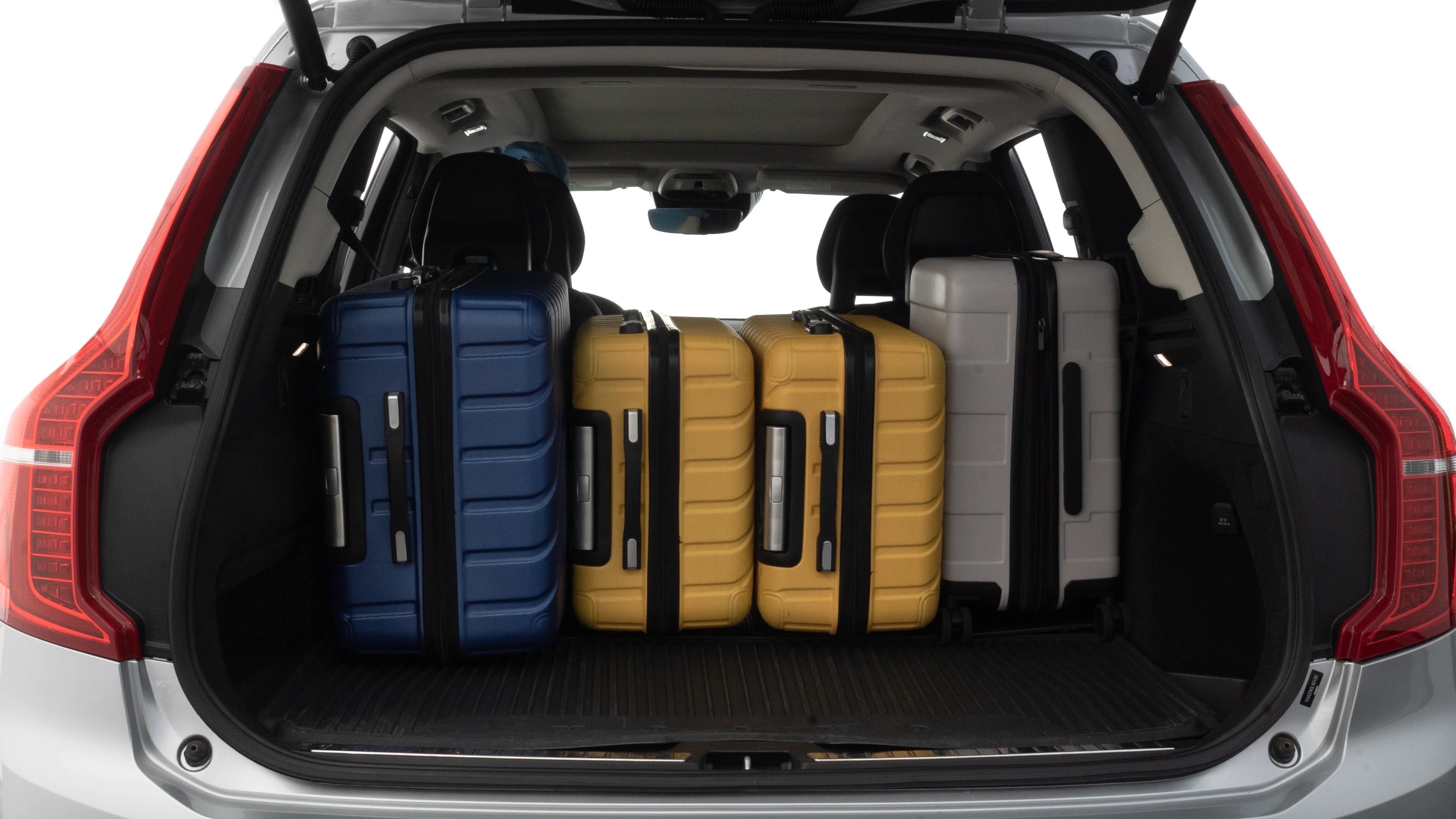 The trunk lid is open, showing full view of the trunk space. One large, two medium, and two small suitcases are placed inside.