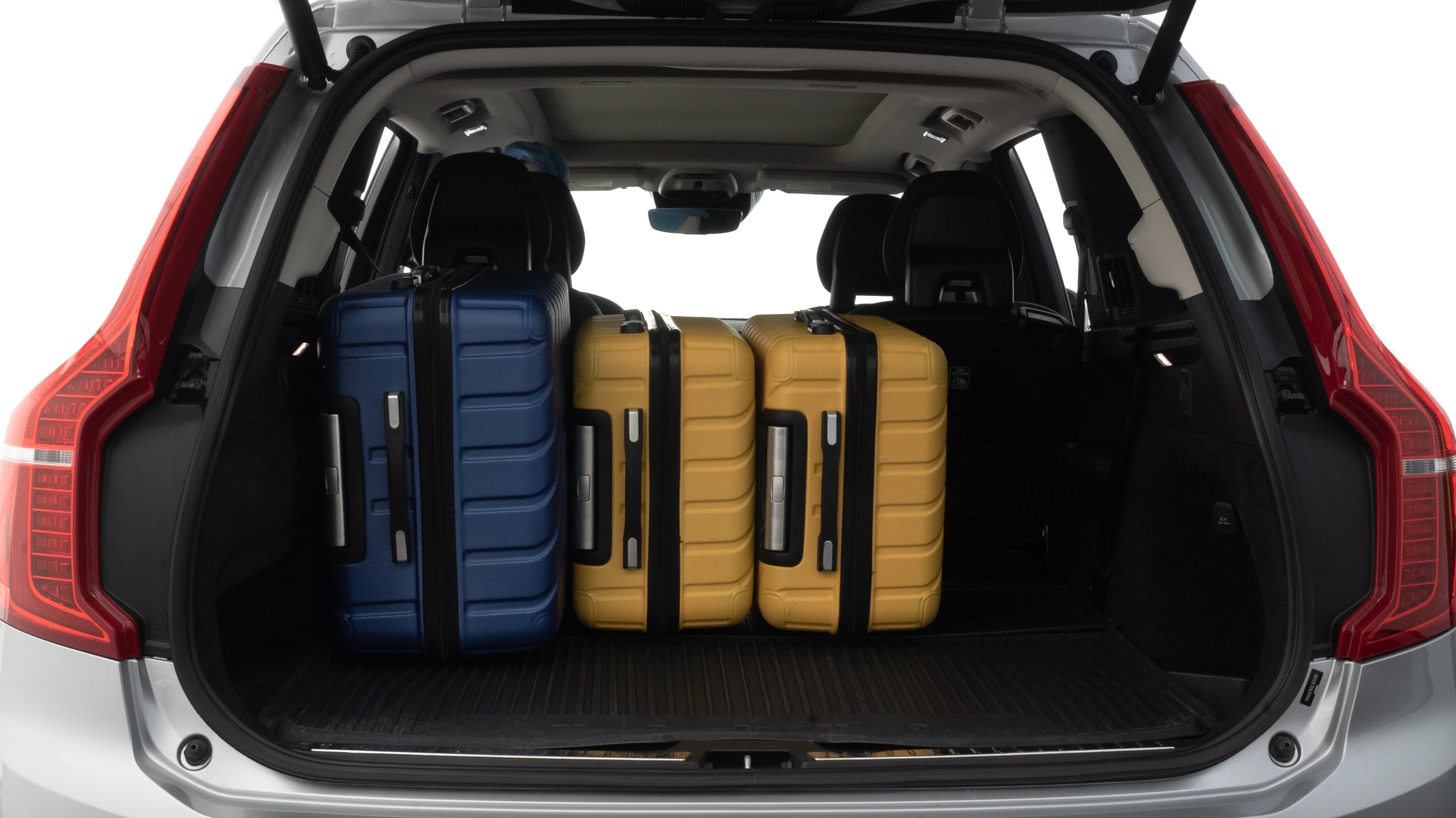 The trunk lid is open, showing full view of the trunk space. One large, two medium, and two small suitcases are placed inside.