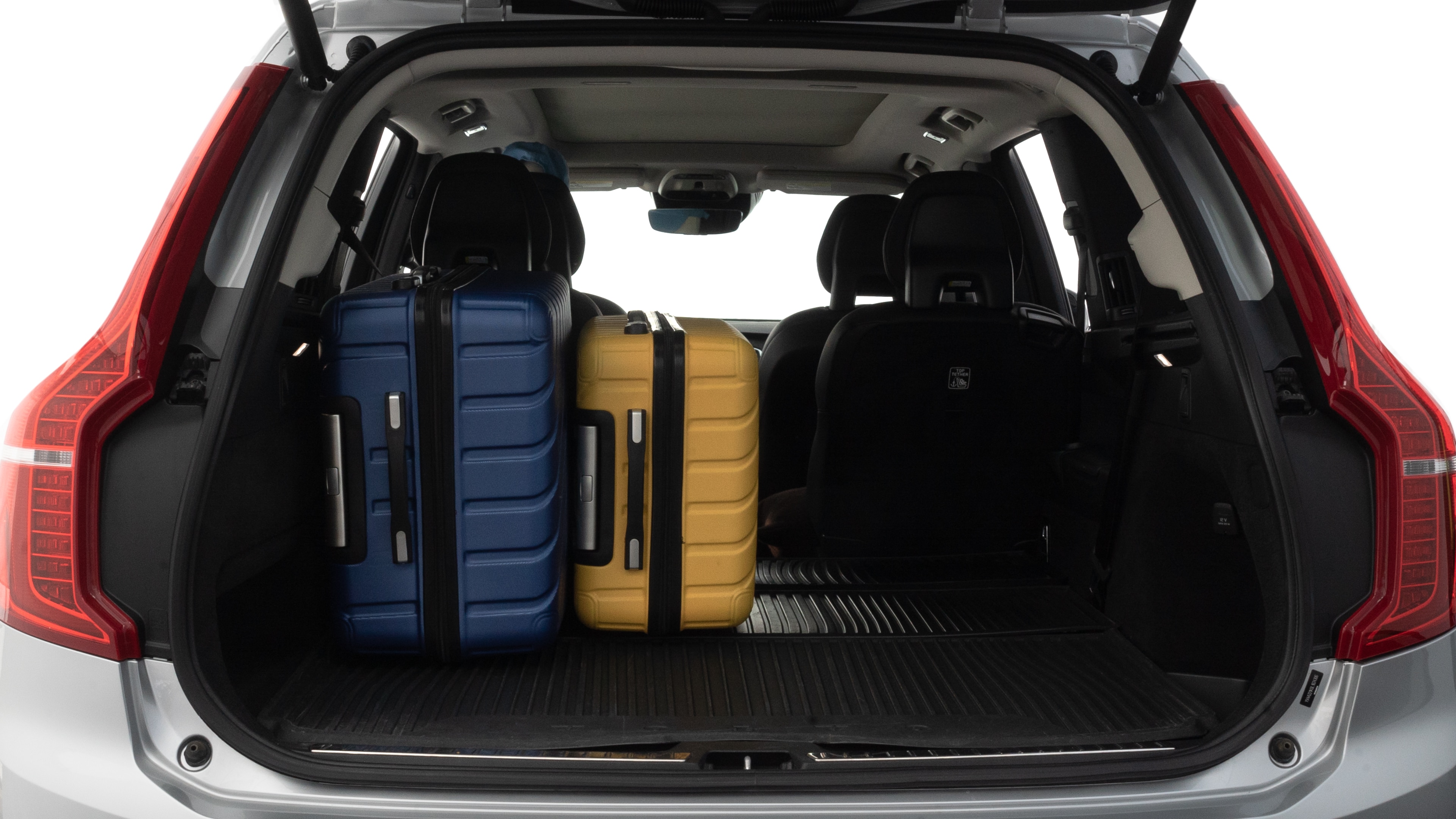 The trunk lid is open, showing full view of the trunk space. One large, two medium, and two small suitcases are placed inside.