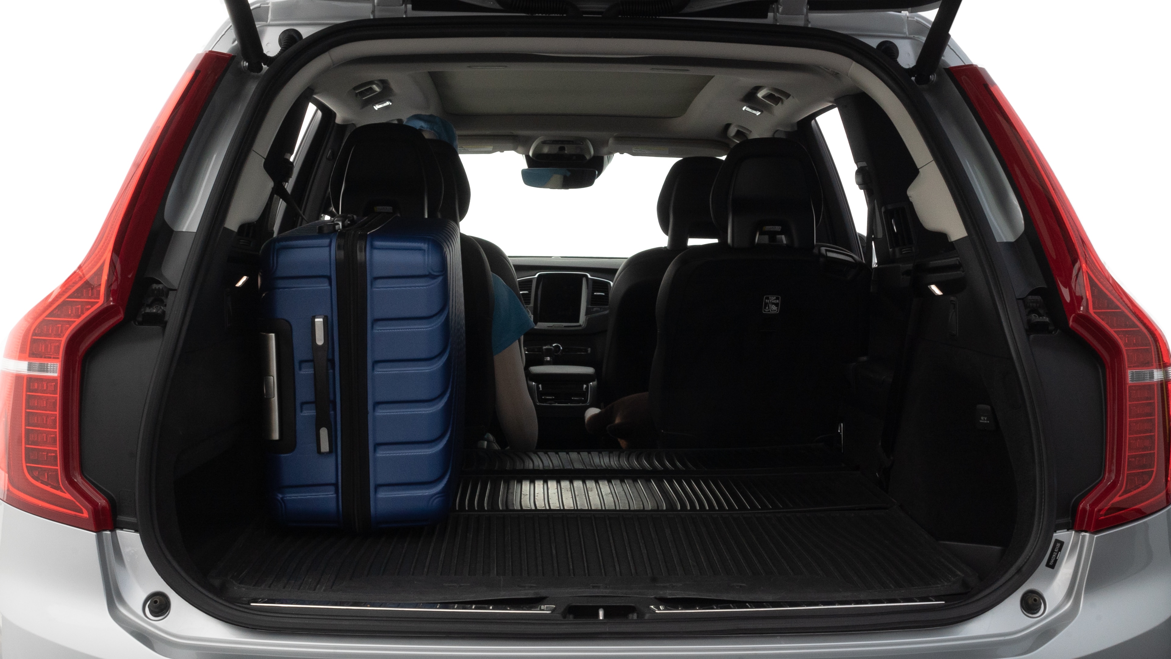 The trunk lid is open, showing full view of the trunk space. One large, two medium, and two small suitcases are placed inside.