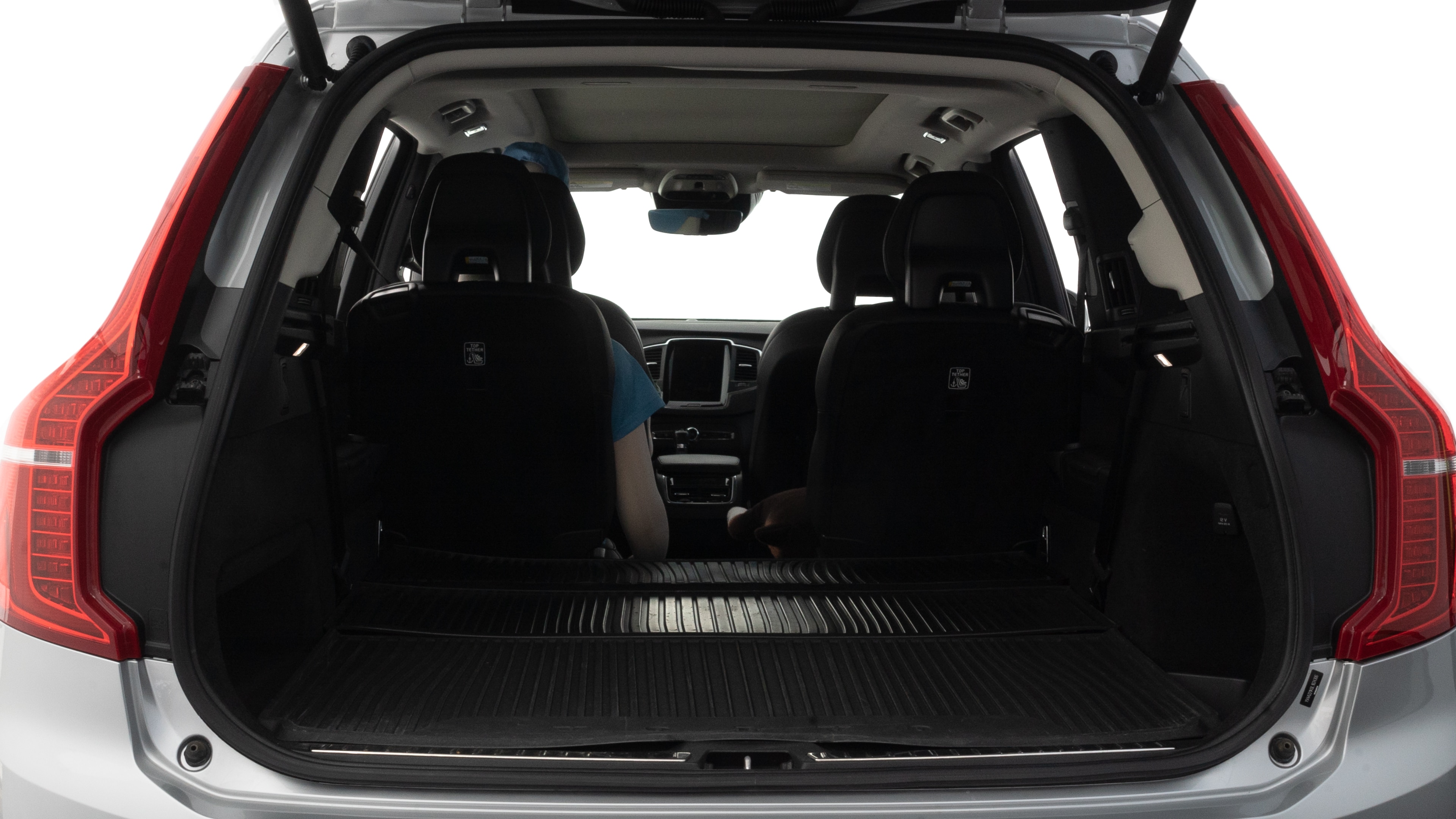 The trunk lid is open, showing full view of the trunk space. One large, two medium, and two small suitcases are placed inside.