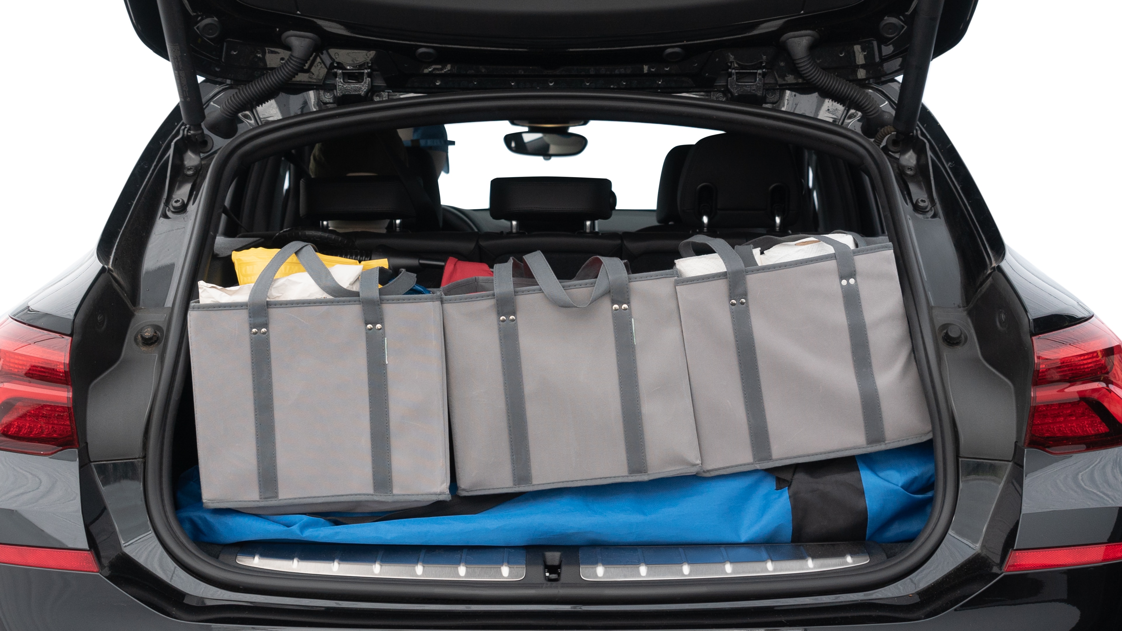 The trunk lid is open showing full view of the trunk. A baby stroller, three grocery carriers, two camping chairs in the carrying bag, and a set of golf clubs are placed inside.
