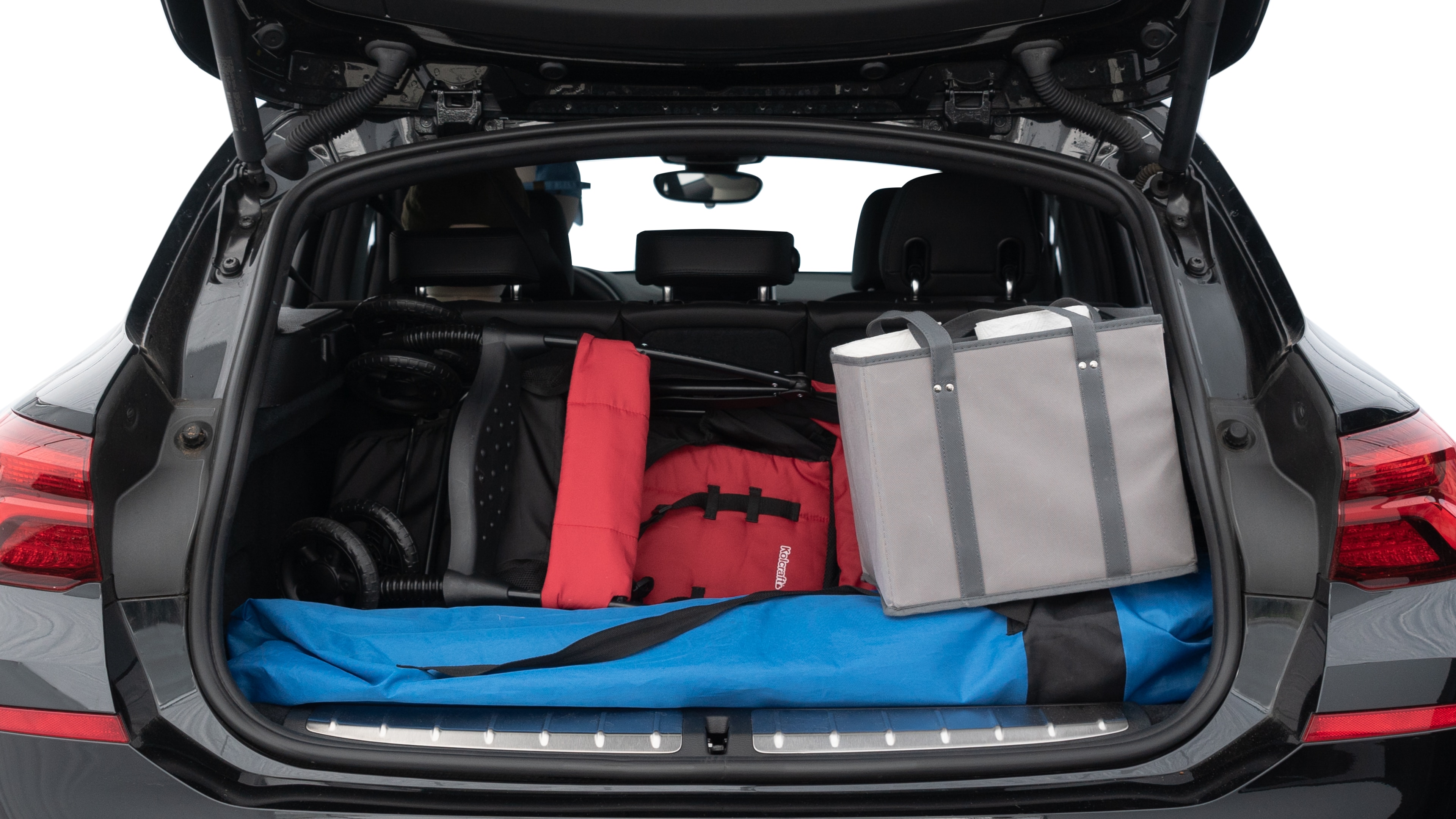 The trunk lid is open showing full view of the trunk. A baby stroller, three grocery carriers, two camping chairs in the carrying bag, and a set of golf clubs are placed inside.