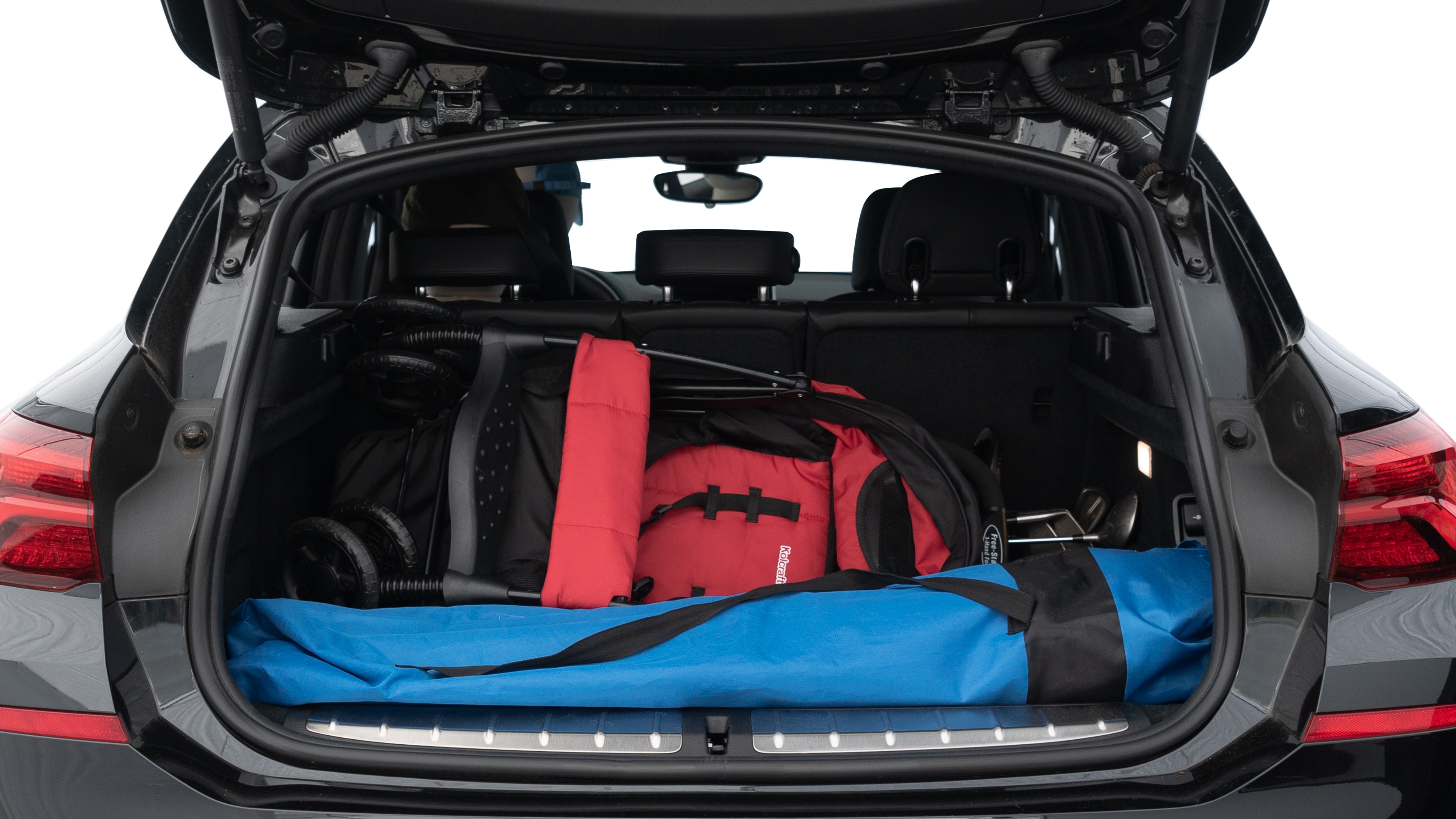 The trunk lid is open showing full view of the trunk. A baby stroller, three grocery carriers, two camping chairs in the carrying bag, and a set of golf clubs are placed inside.