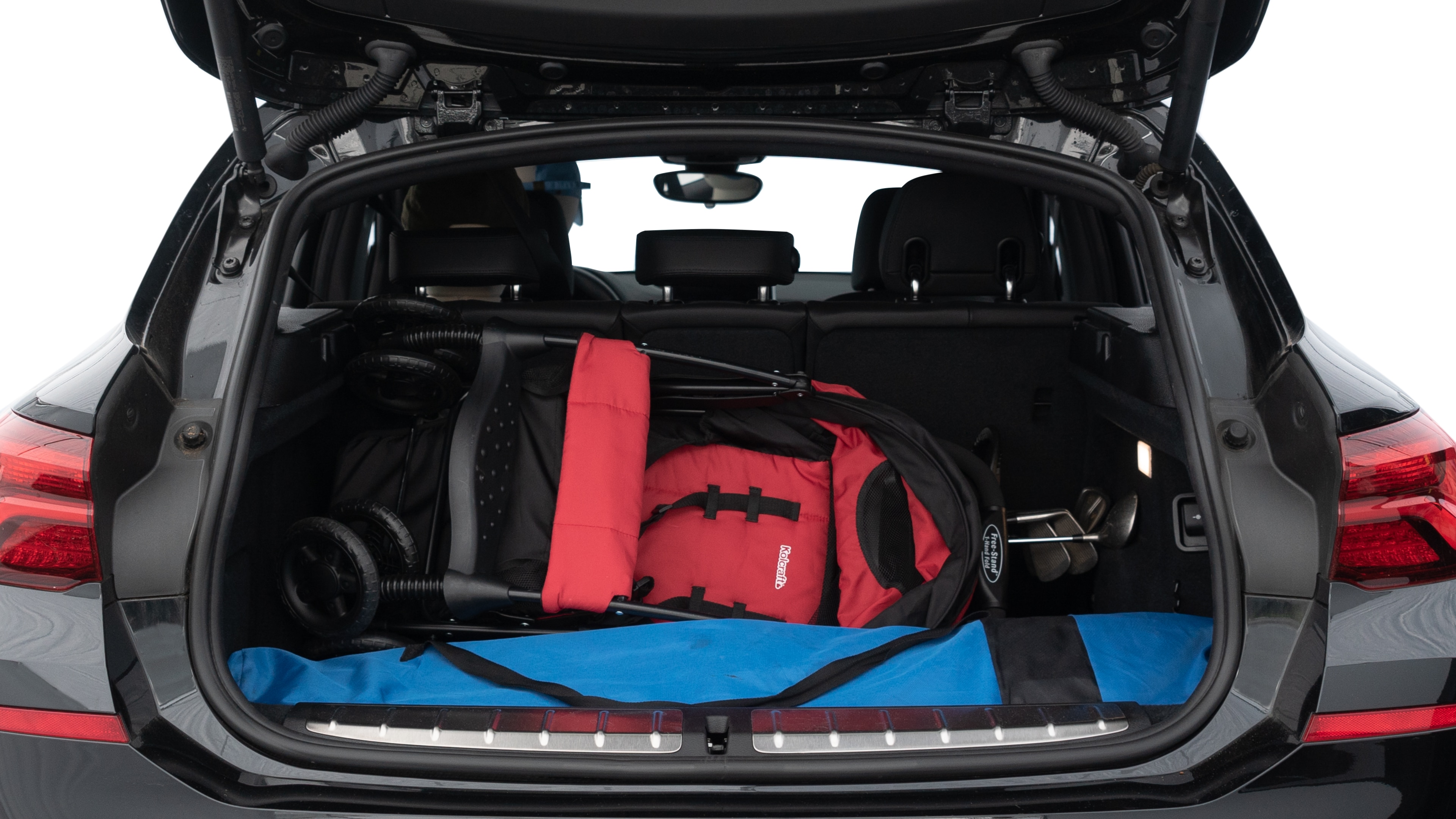 The trunk lid is open showing full view of the trunk. A baby stroller, three grocery carriers, two camping chairs in the carrying bag, and a set of golf clubs are placed inside.