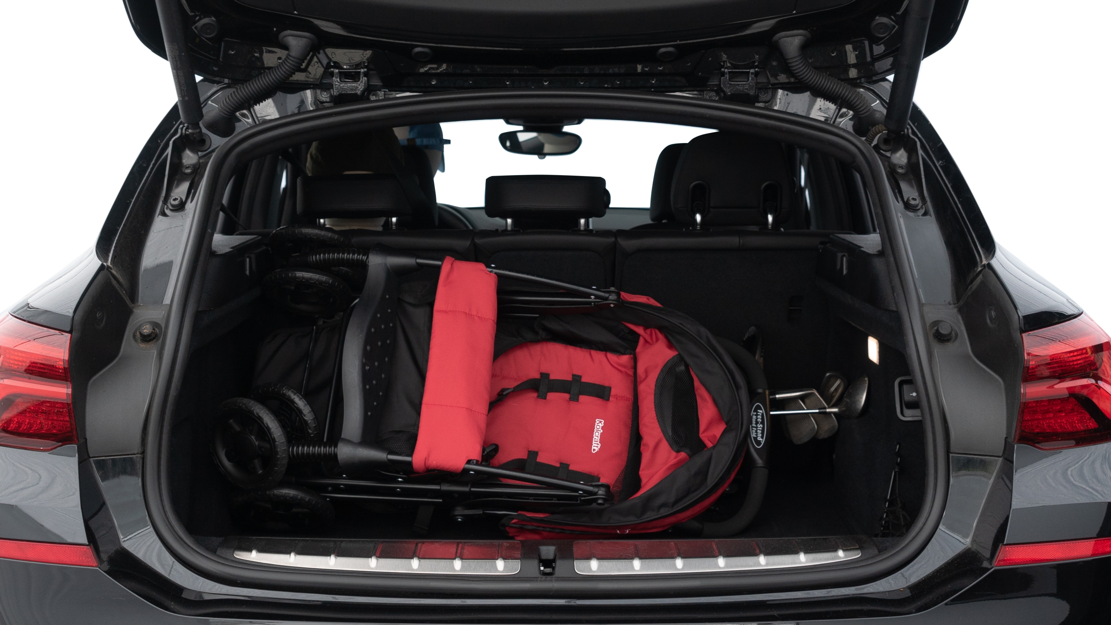 The trunk lid is open showing full view of the trunk. A baby stroller, three grocery carriers, two camping chairs in the carrying bag, and a set of golf clubs are placed inside.
