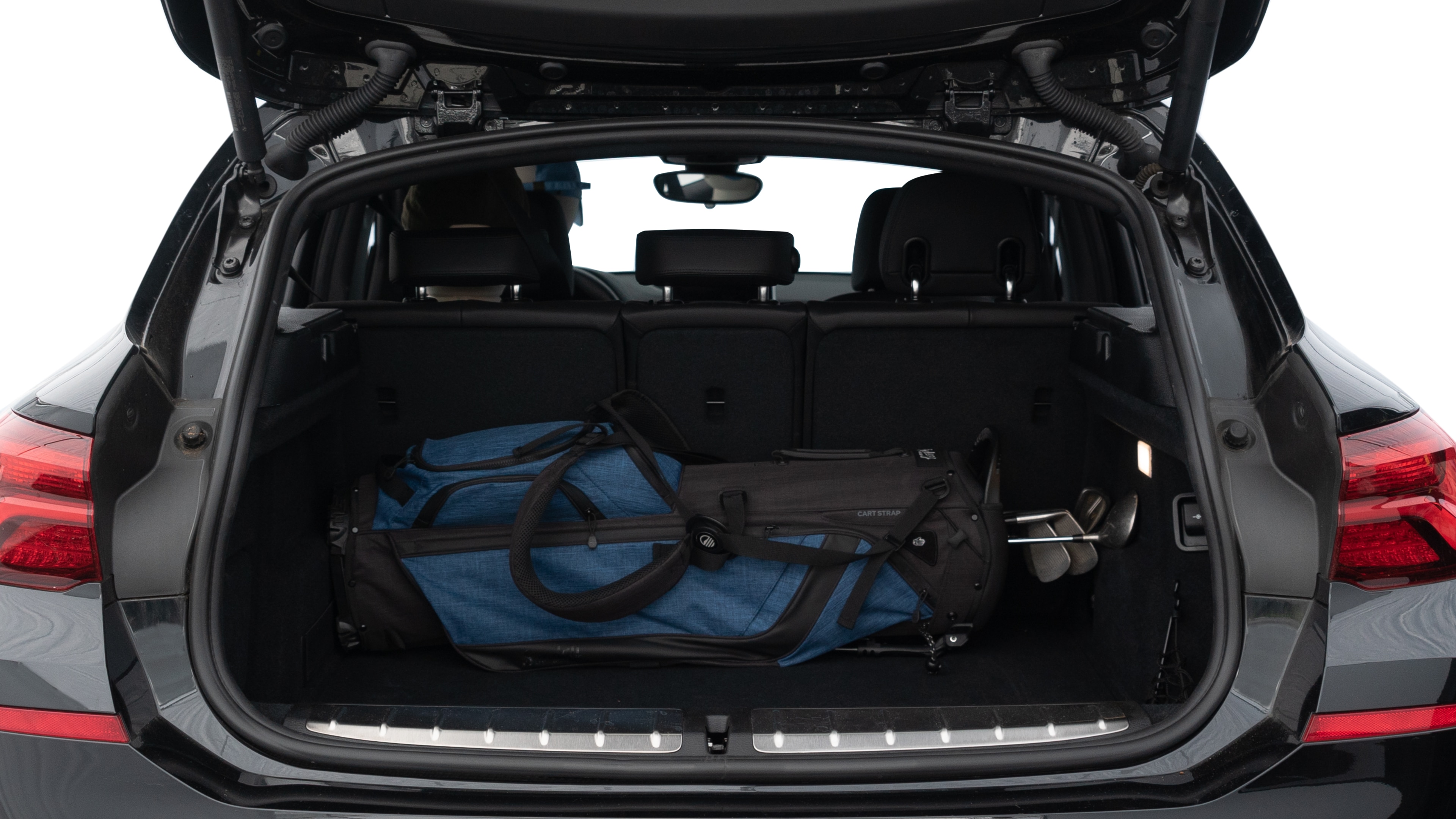The trunk lid is open showing full view of the trunk. A baby stroller, three grocery carriers, two camping chairs in the carrying bag, and a set of golf clubs are placed inside.