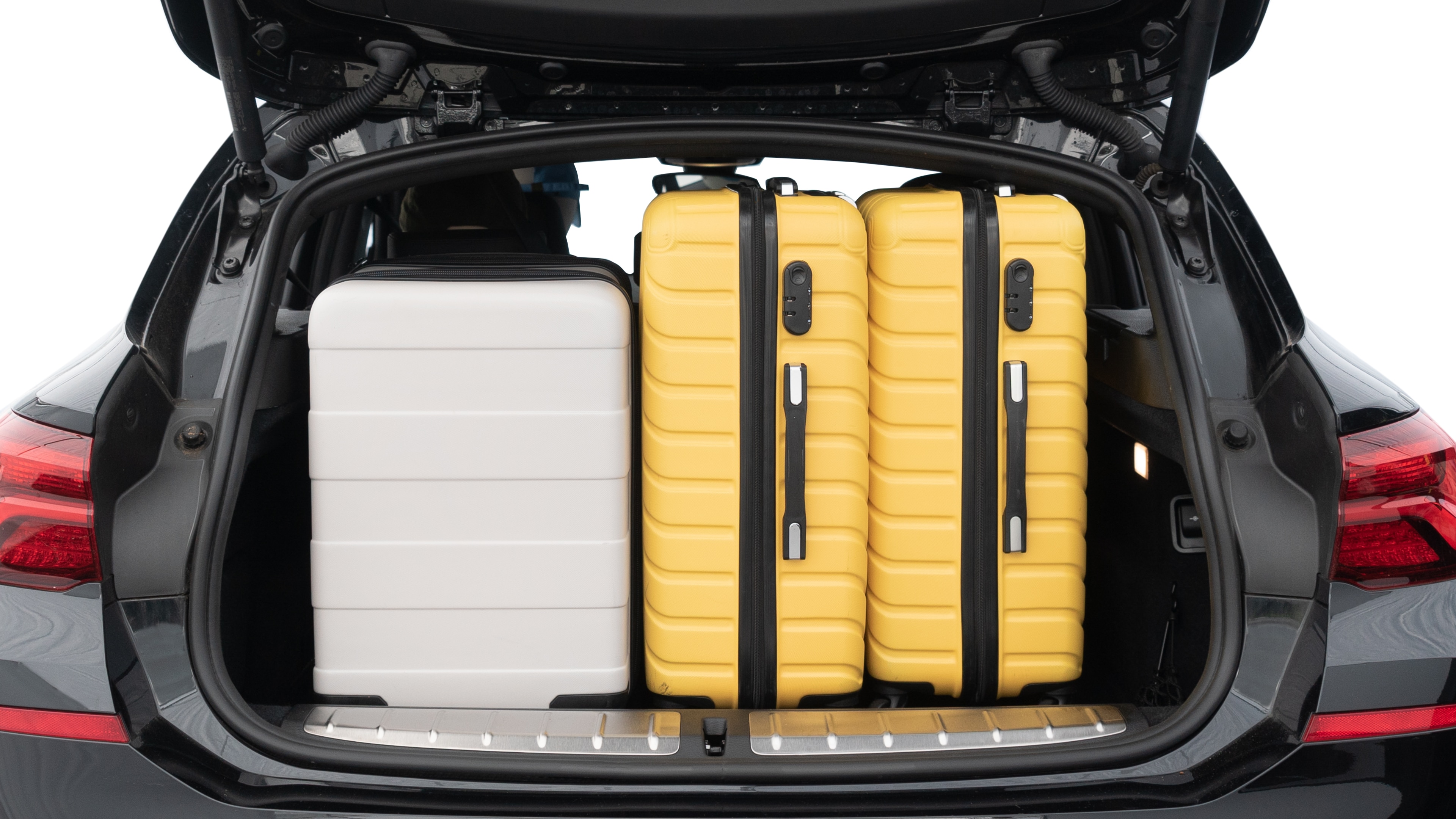 The trunk lid is open, showing full view of the trunk space. Two medium and two small suitcases are placed inside.