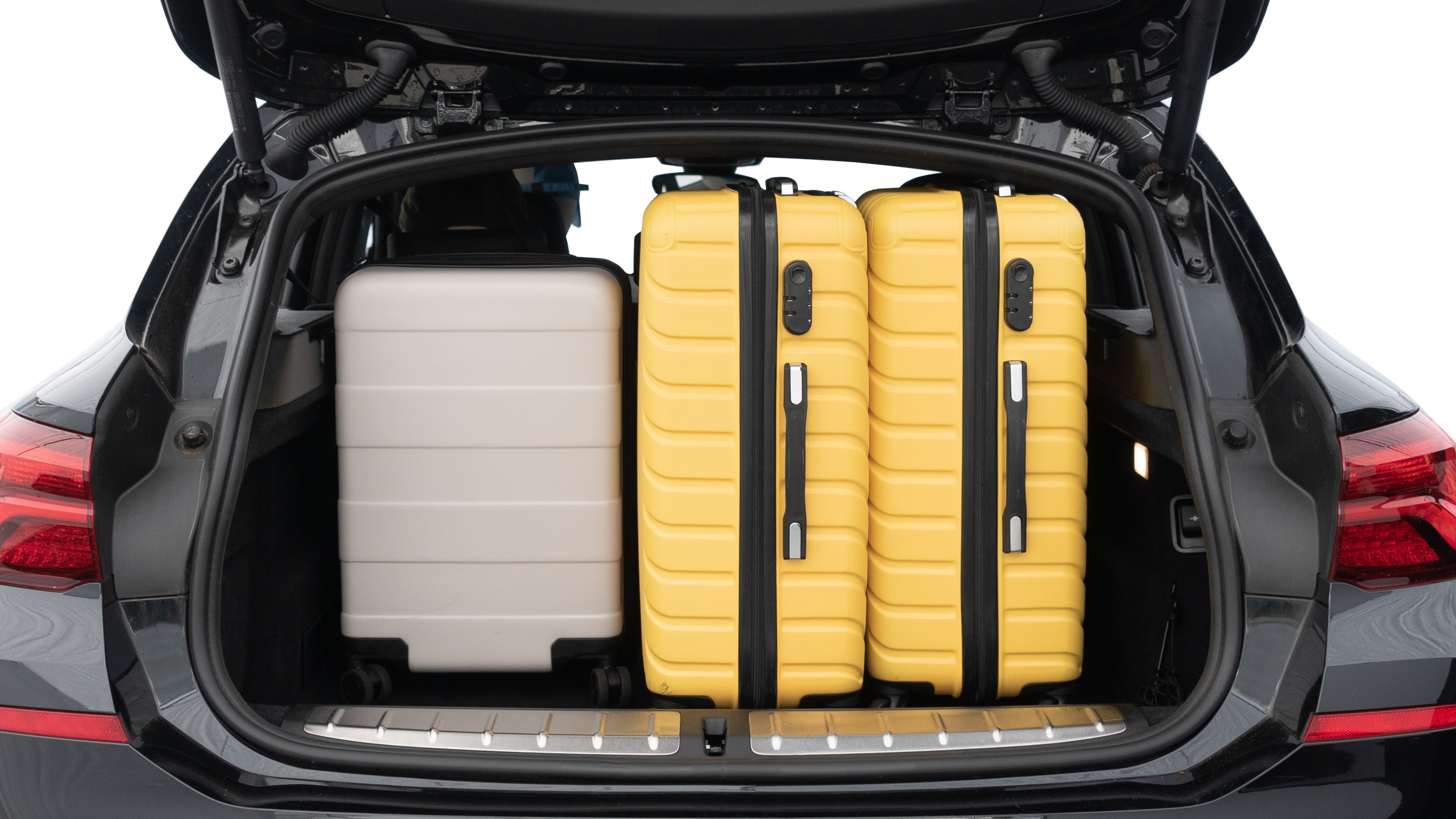 The trunk lid is open, showing full view of the trunk space. Two medium and two small suitcases are placed inside.