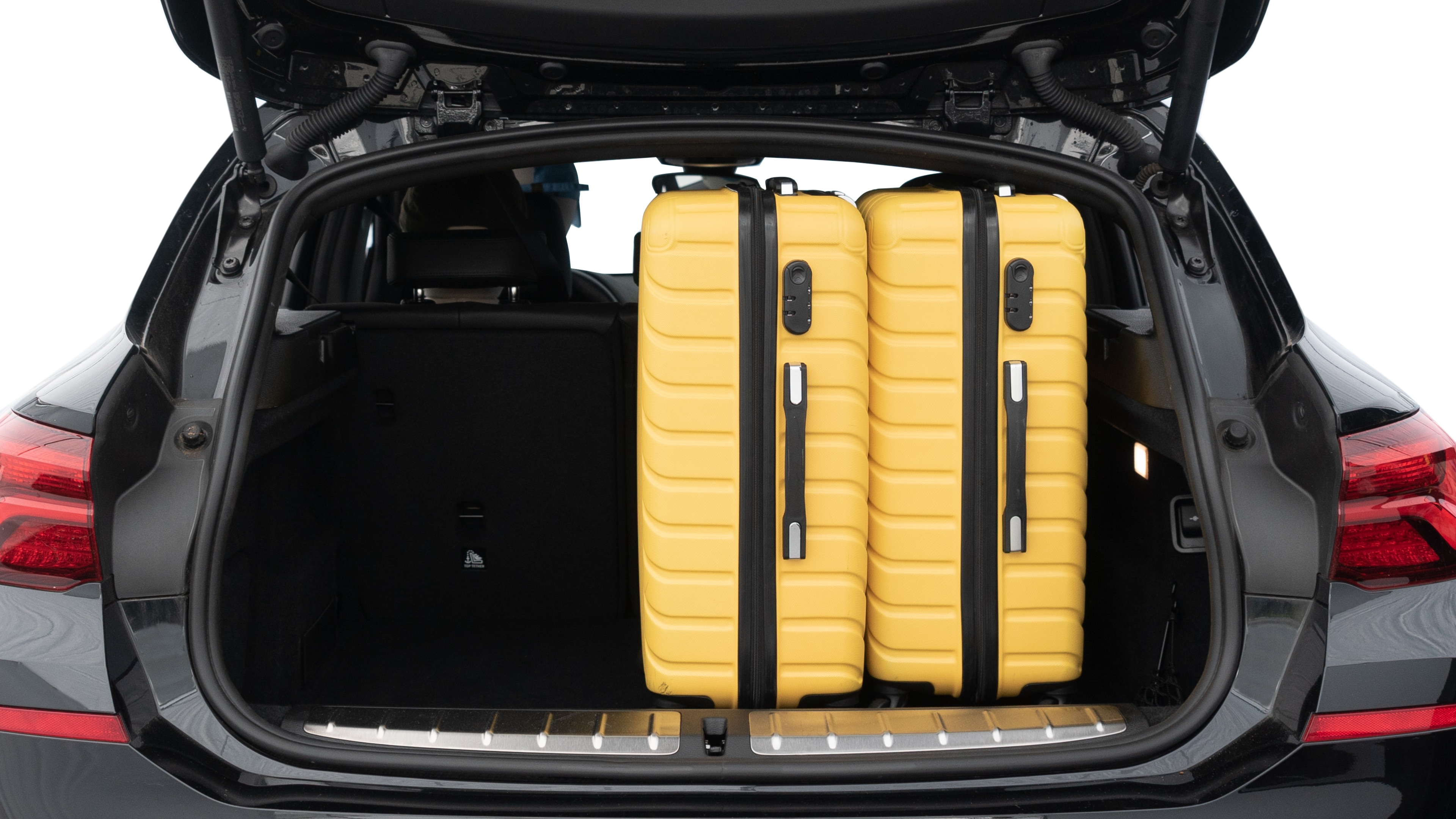 The trunk lid is open, showing full view of the trunk space. Two medium and two small suitcases are placed inside.