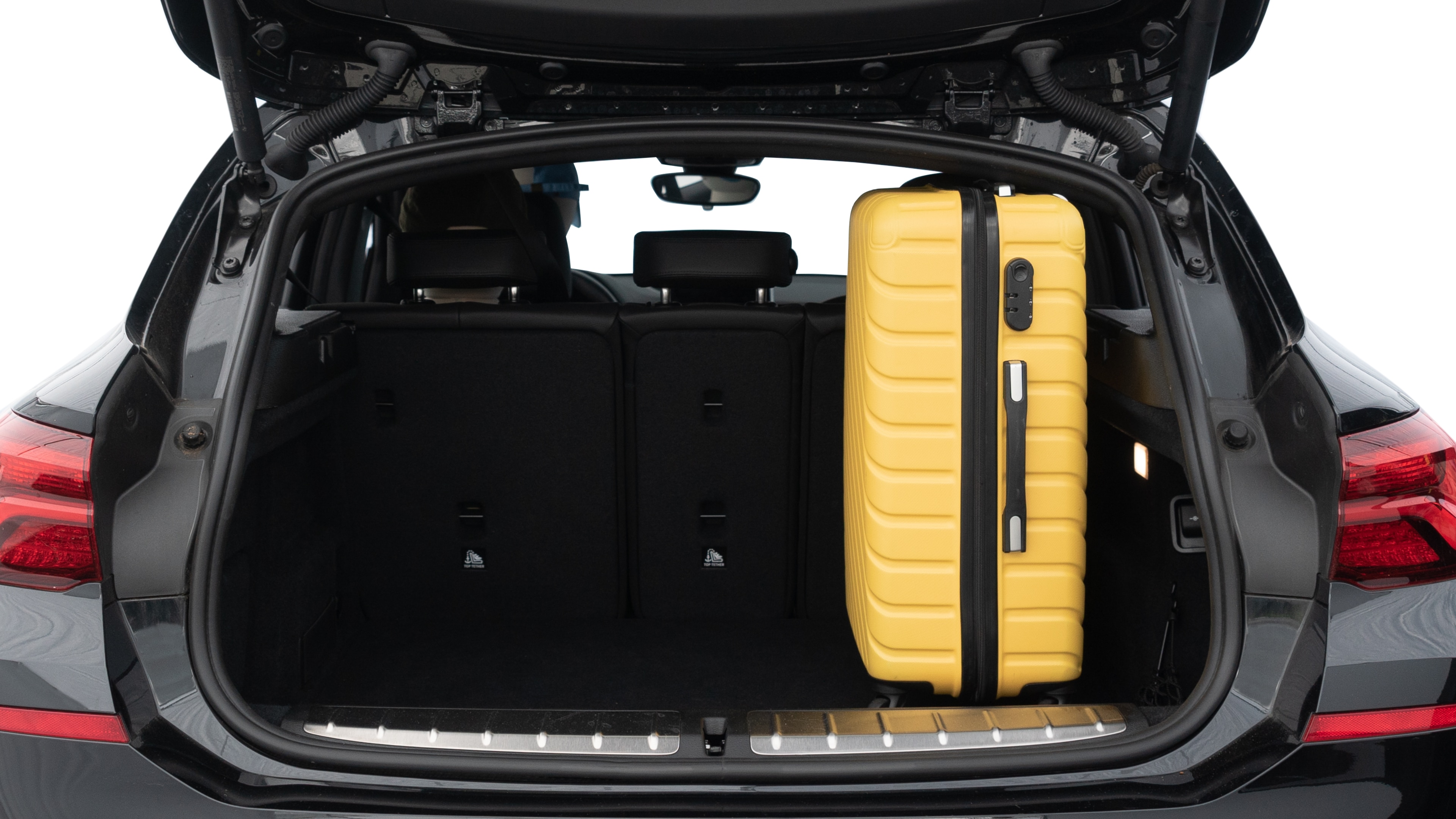 The trunk lid is open, showing full view of the trunk space. Two medium and two small suitcases are placed inside.
