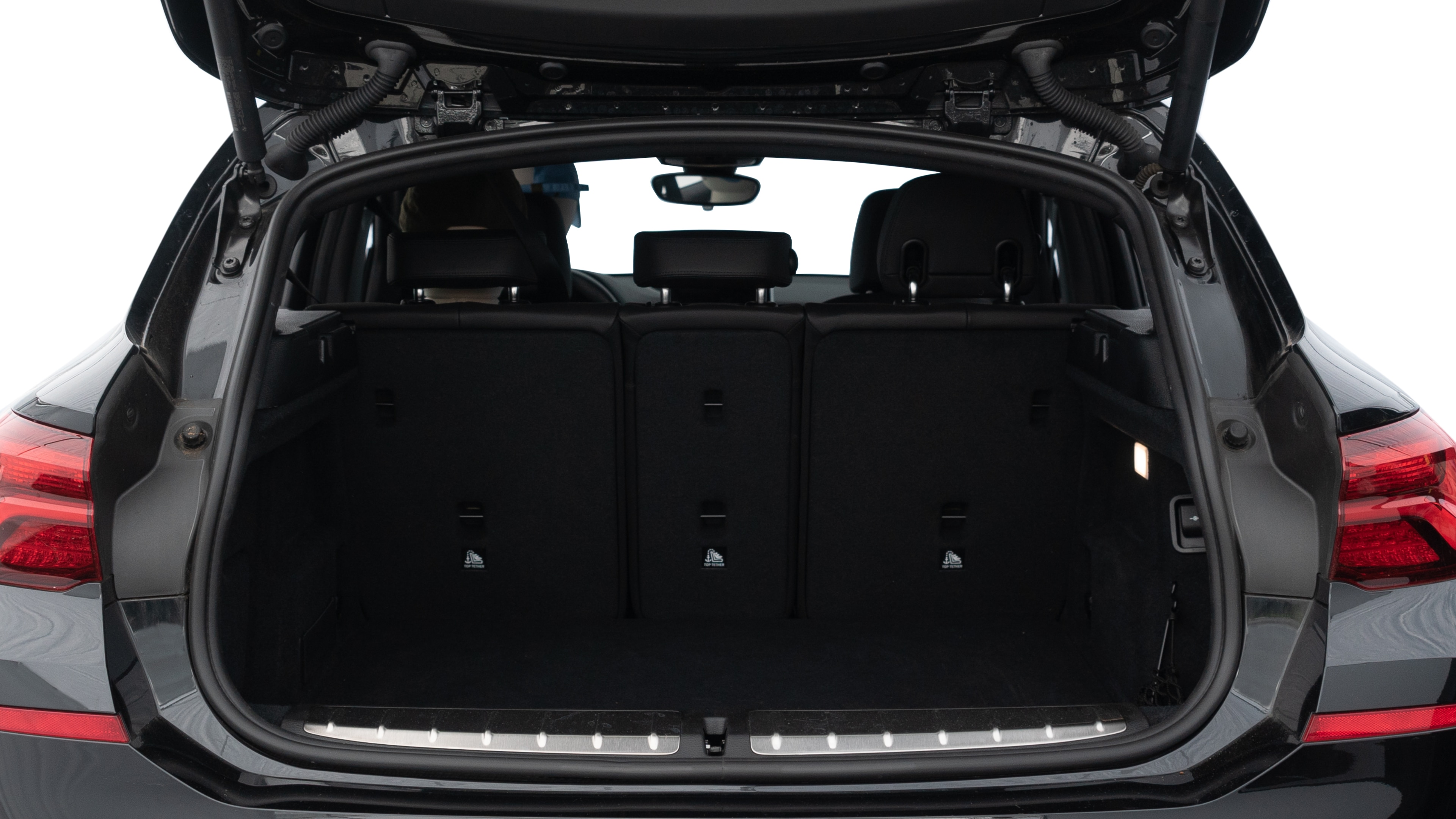The trunk lid is open, showing full view of the trunk space. Two medium and two small suitcases are placed inside.