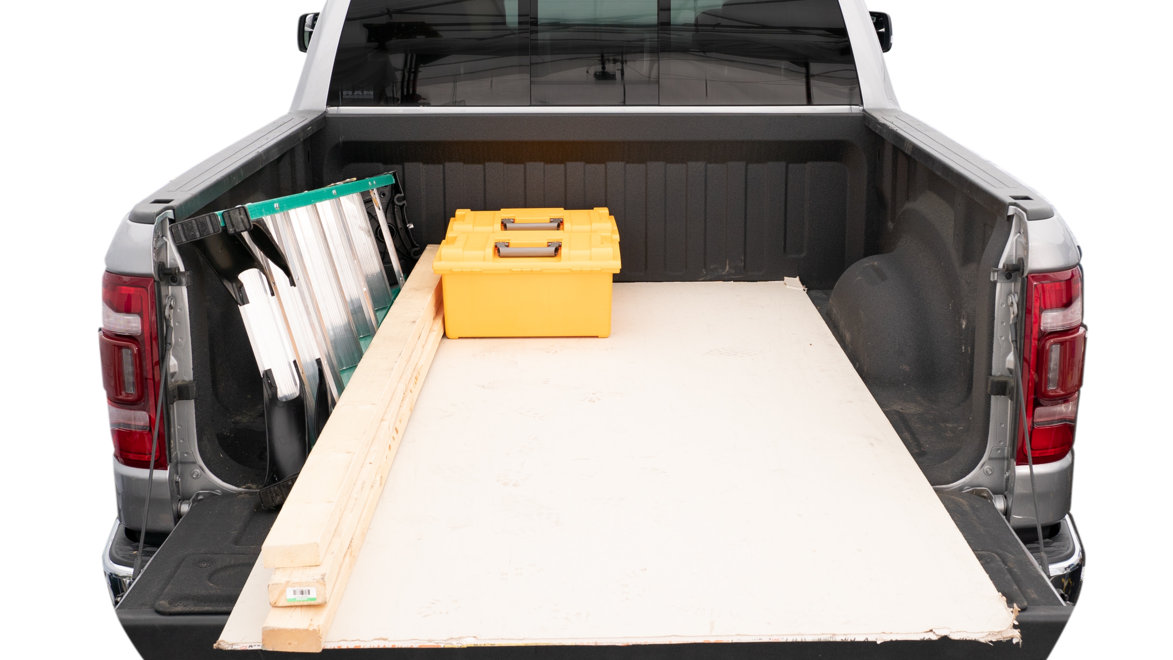 The trunk area is open giving a full view of the trunk area. A ladder, three 2 by 4 framing studs, two tool boxes and a 4 by 8 drywall sheet are placed inside. 